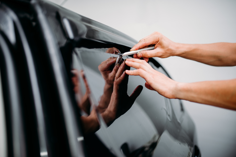 Hand schneidet mit Messer Autoglasfolie