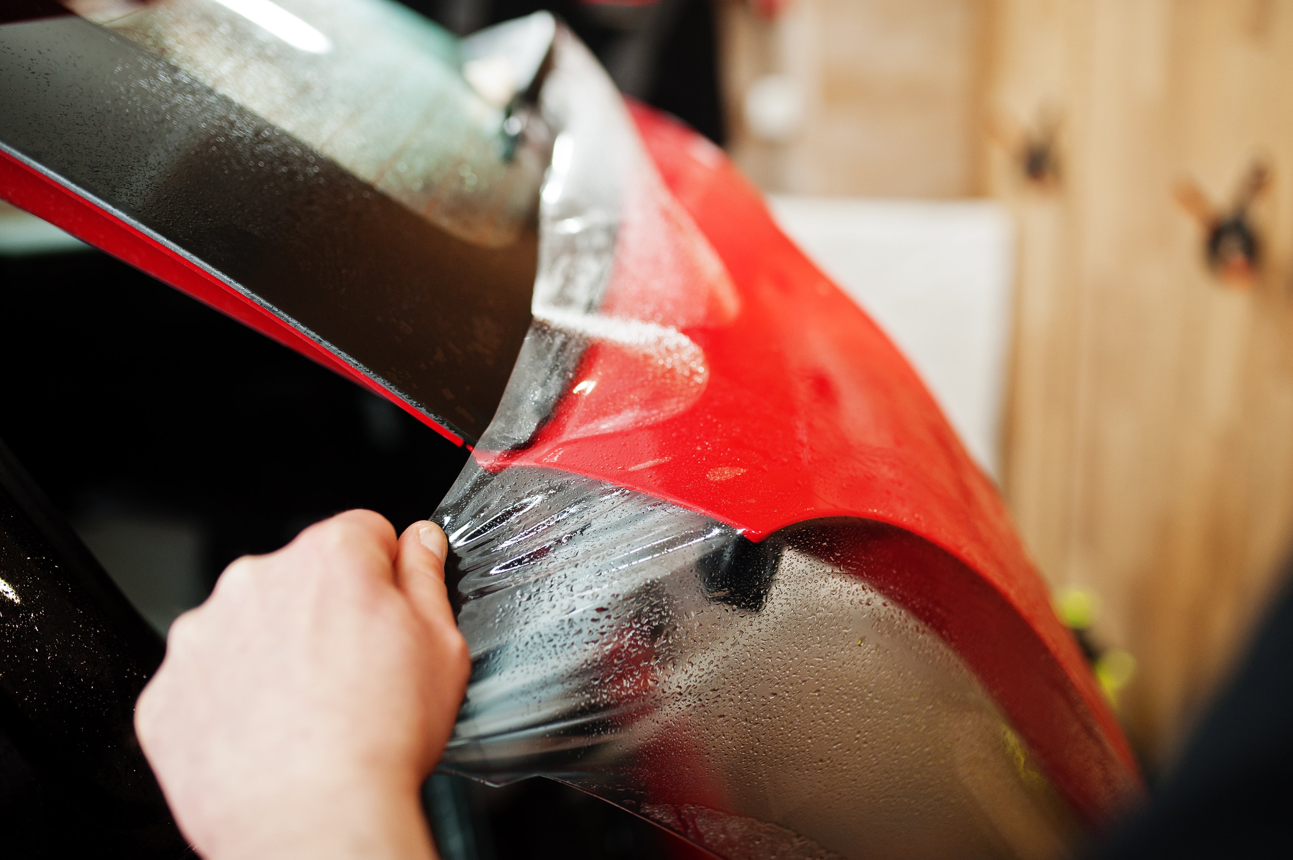 Hand zieht PPF über Fahrzeugoberfläche