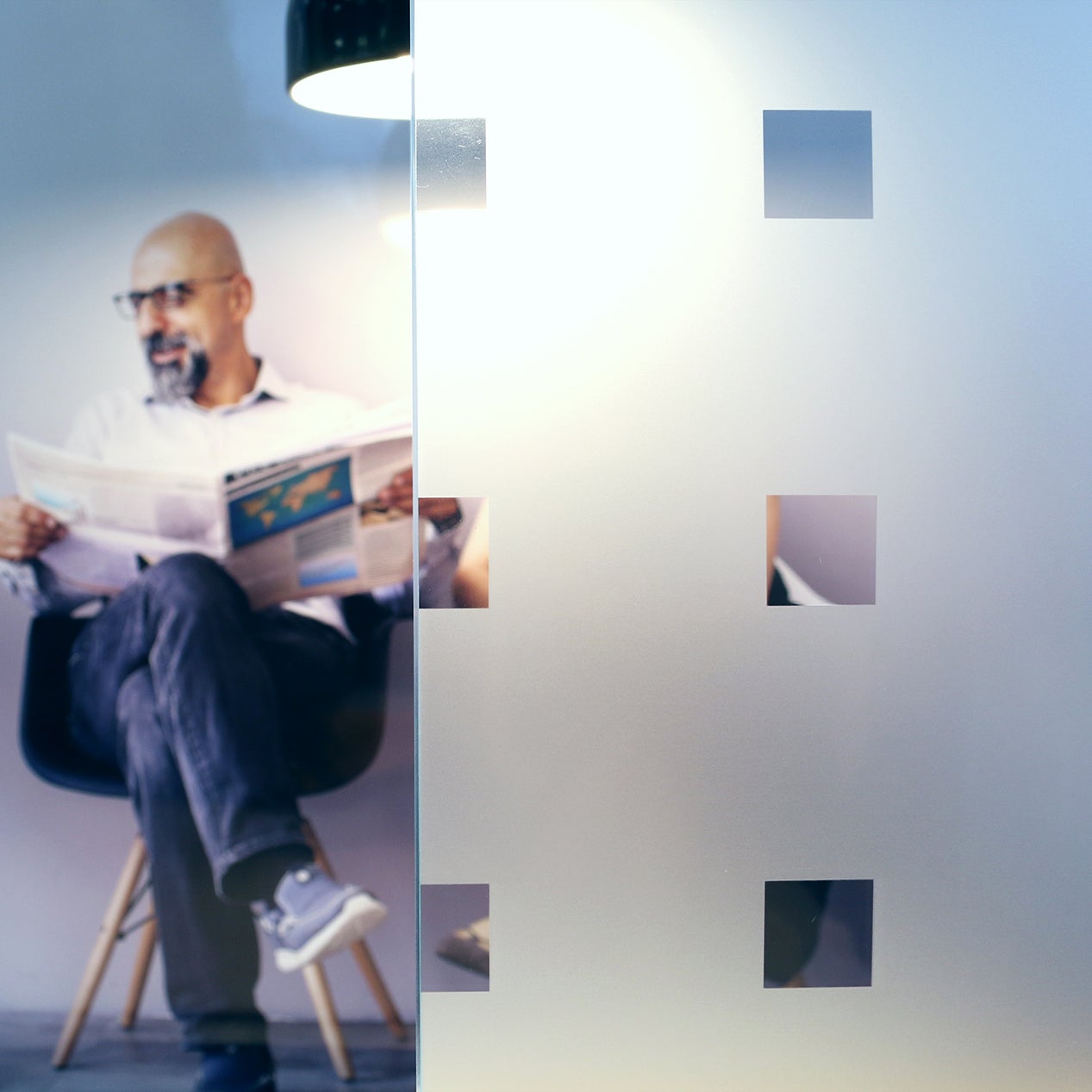 Anwendungsbild Dekorfolie CDF 2461 Quadrate, Innenverlegung, Personen hinter Folie, Folie in Sandstrahloptik, Quadrate klar, 20x20mm hoch, Abstand 50mm, Sichtschutz