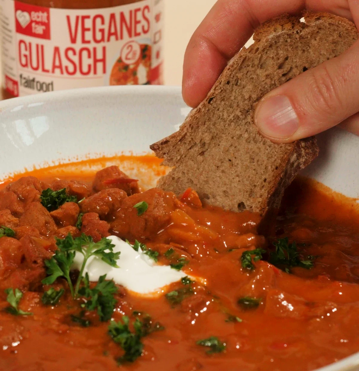 stueck brot wird in gulasch auf teller gedippt