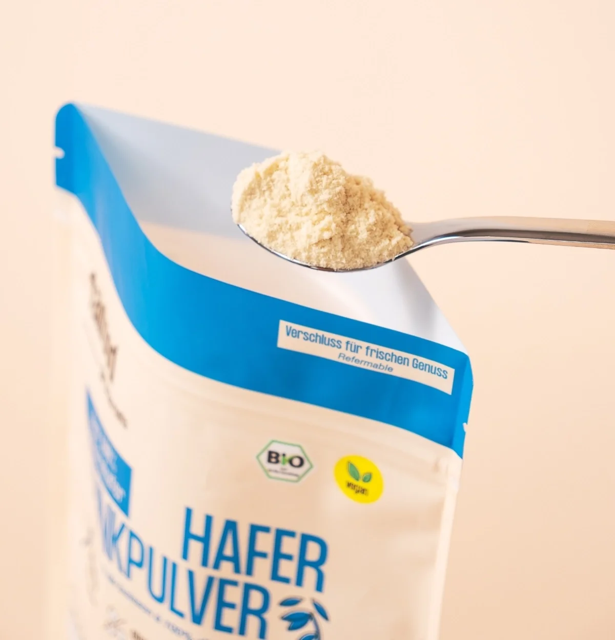 Löffel mit Haferdrinkpulver wird aus dem Beutel gehoben