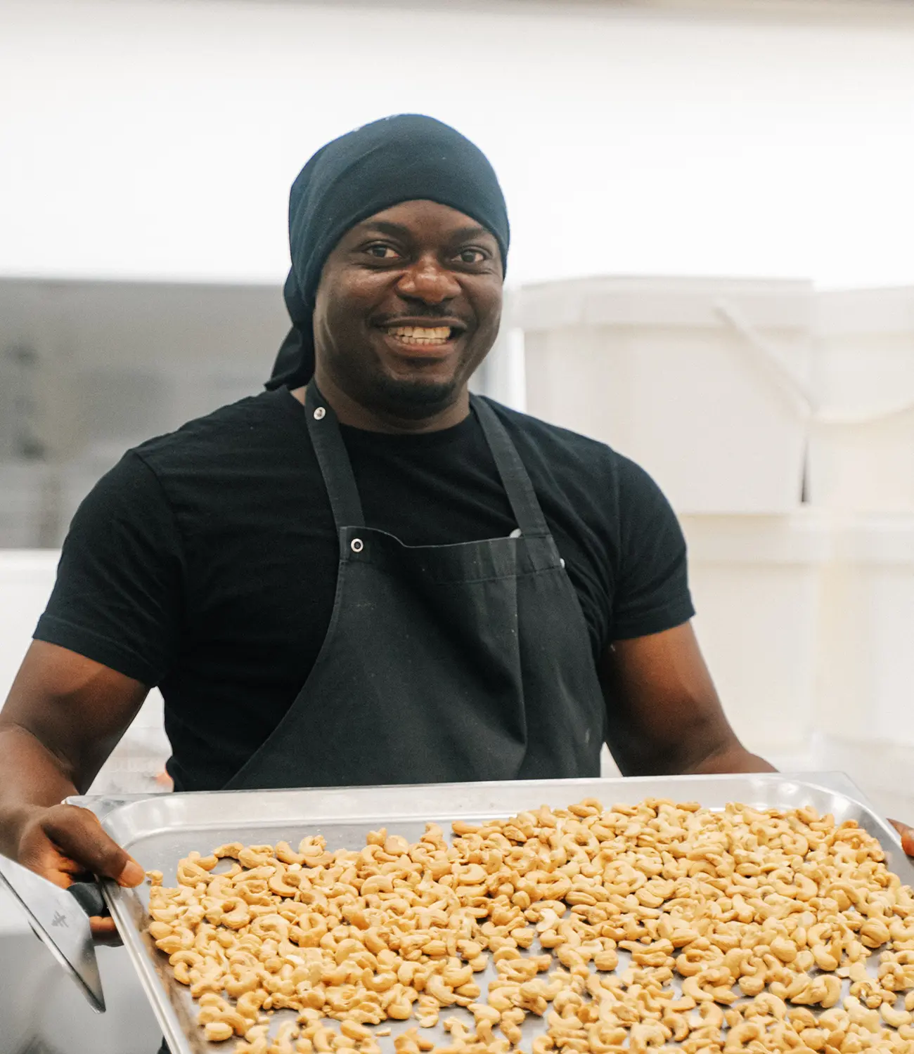 Mann haelt Blech mit vielen geroesteten Cashews