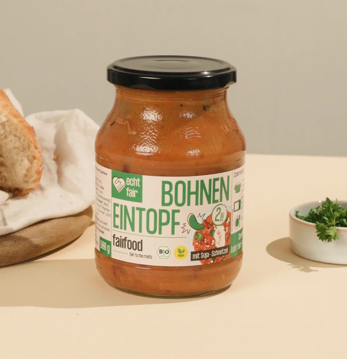 glas bohnen eintopf neben brot und kraeutern