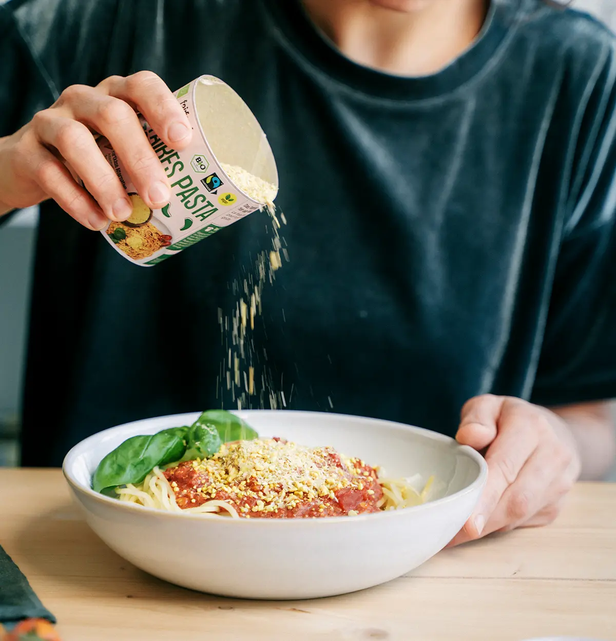 Spaghetti mit Nussbolognese in einem Teller, Pasta Topping wird darüber gestreut
