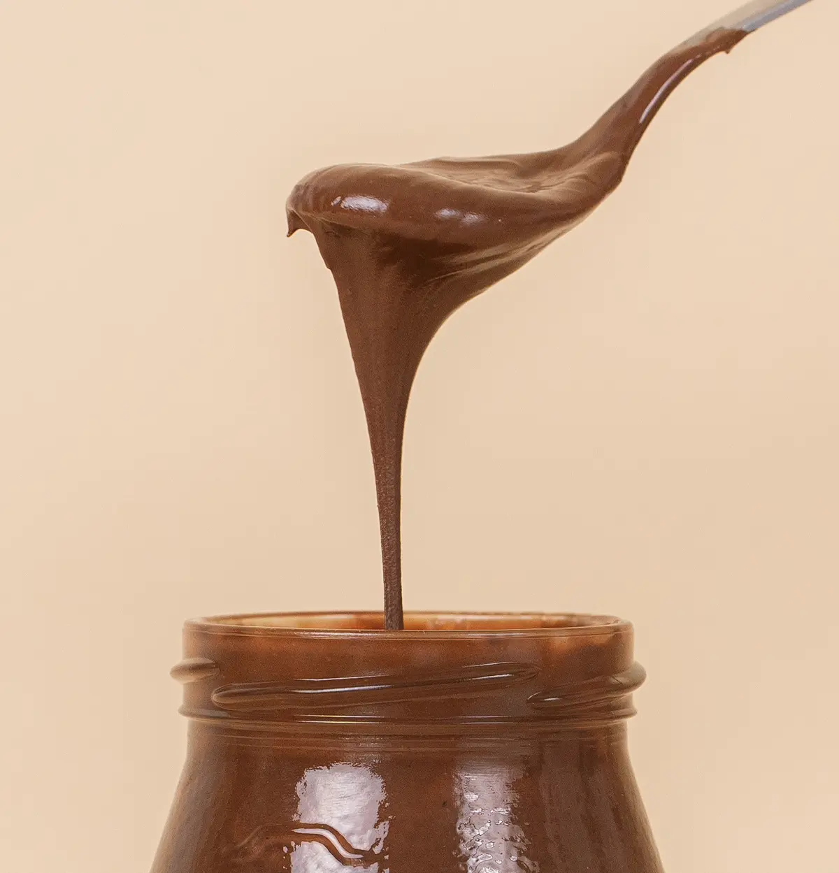 Fairchoc Haselnuss im Pfandglas mit einem Löffel bei dem der die Schokocreme in das Glas tropft