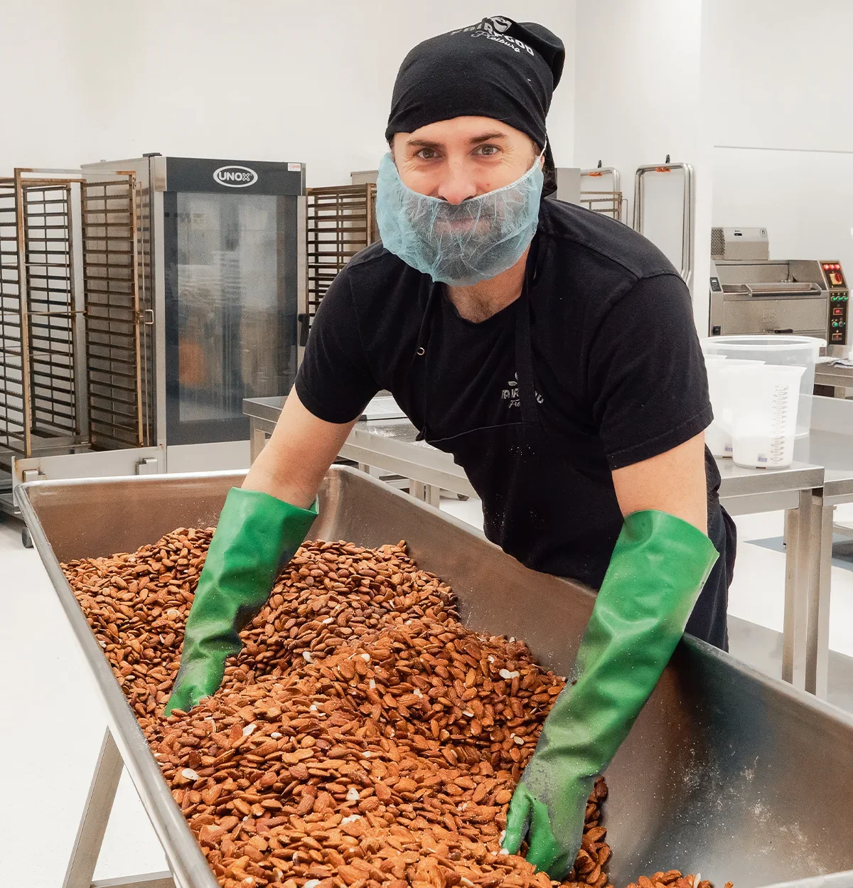 Julian vermengt gesalzene Mandeln in der Produktionskueche