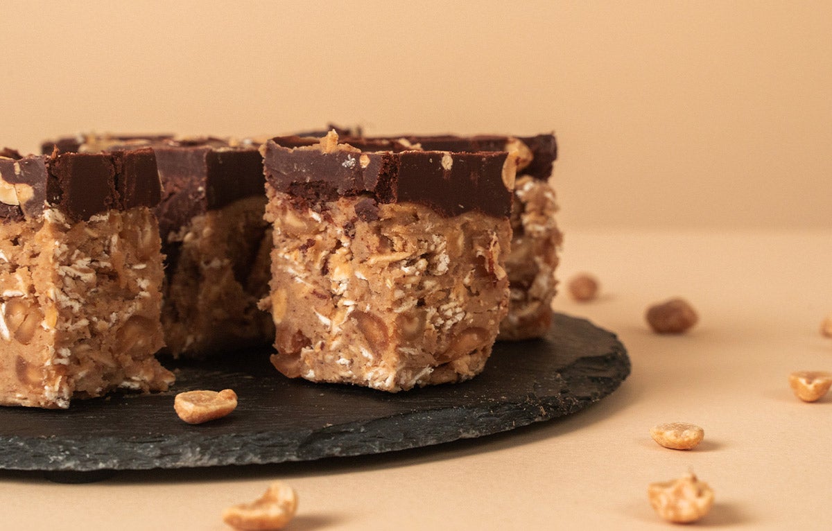 Vegane Snicker-Riegel mit fairfood Erdnüssen, Bio Erdnussmus und fairen Bio-Datteln Hier siehst du vegane Snicker-Riegel mit fairfood Erdnüssen, Bio Erdnussmus und fairen Bio-Datteln