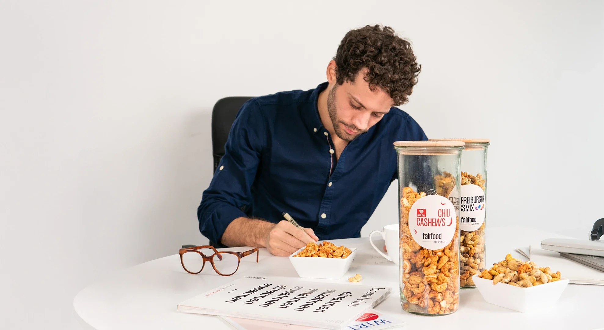 Person sitzt am Schreibtisch, davor Nüsse