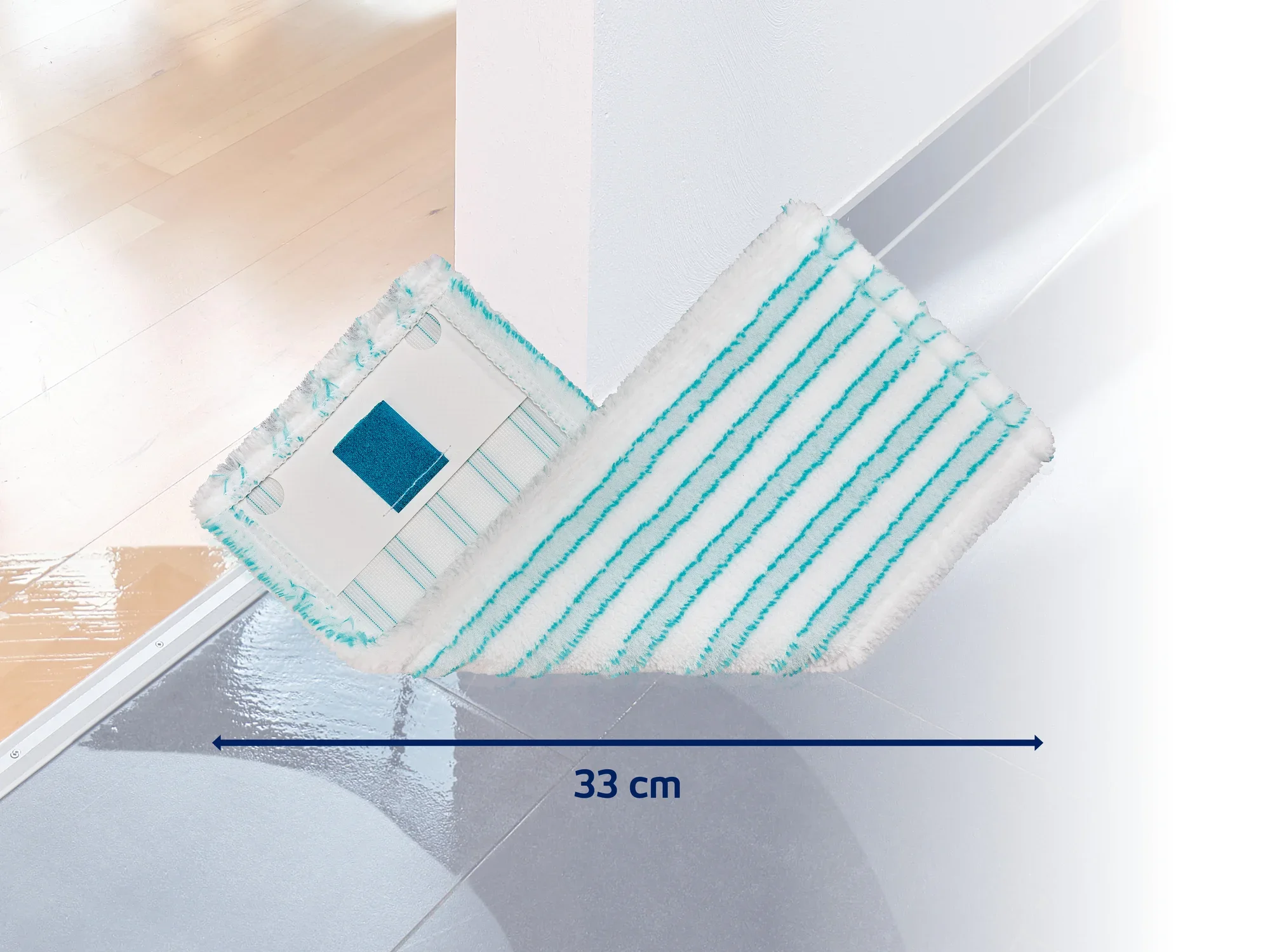 Mop o szerokości 33 cm leży na błyszczącej podstawie. Mop ma biało-niebieskie paski i nadaje się do dokładnego czyszczenia.
