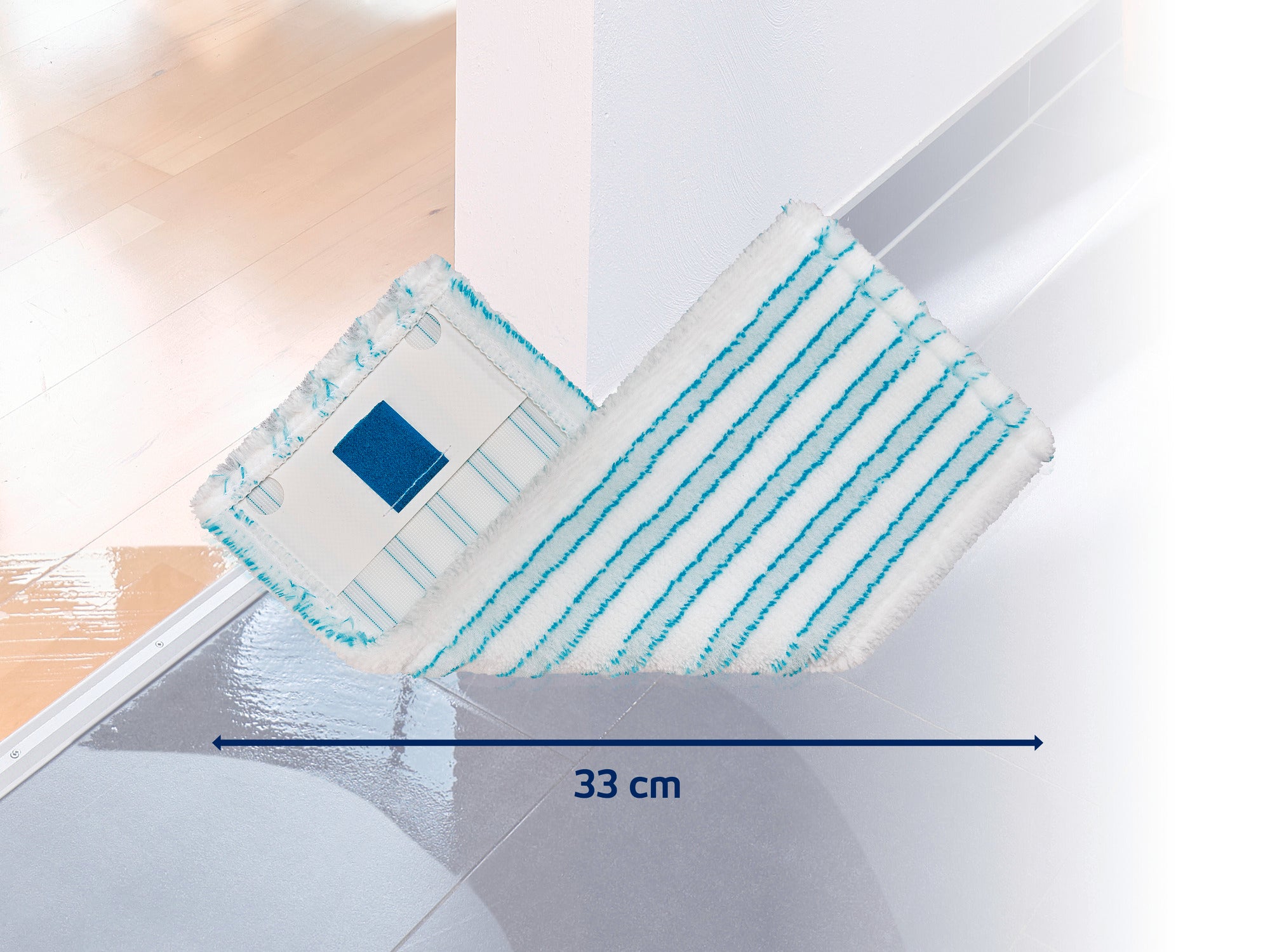 Mop o szerokości 33 cm leży na błyszczącej podstawie. Mop ma biało-niebieskie paski i nadaje się do dokładnego czyszczenia.
