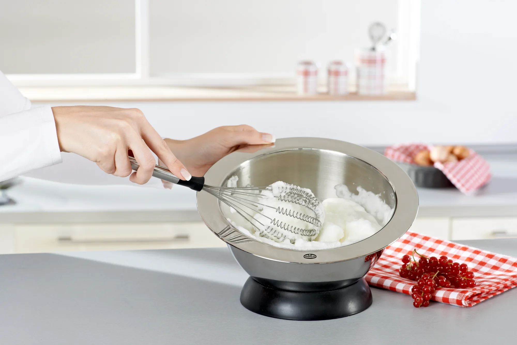 Dans une cuisine moderne, le fouet Speed Quirl S est utilisé pour battre des blancs d'œufs dans un bol en acier inoxydable. Des ustensiles de cuisine sont visibles à l'arrière-plan.