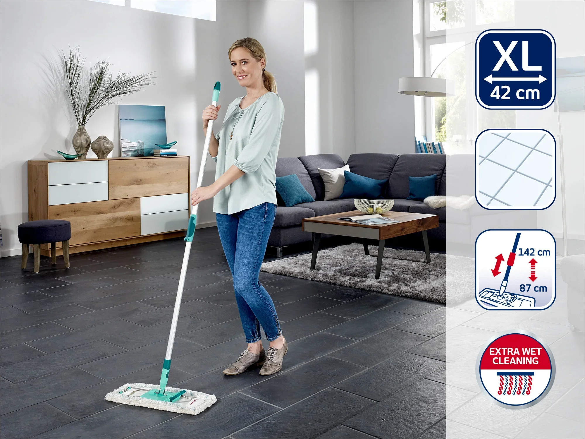 Une femme nettoie le sol d'un salon moderne avec une raclette Leifheit XL de 42 cm. La raclette est dotée d'un manche télescopique réglable de 87 cm à 142 cm et offre un nettoyage extra humide.