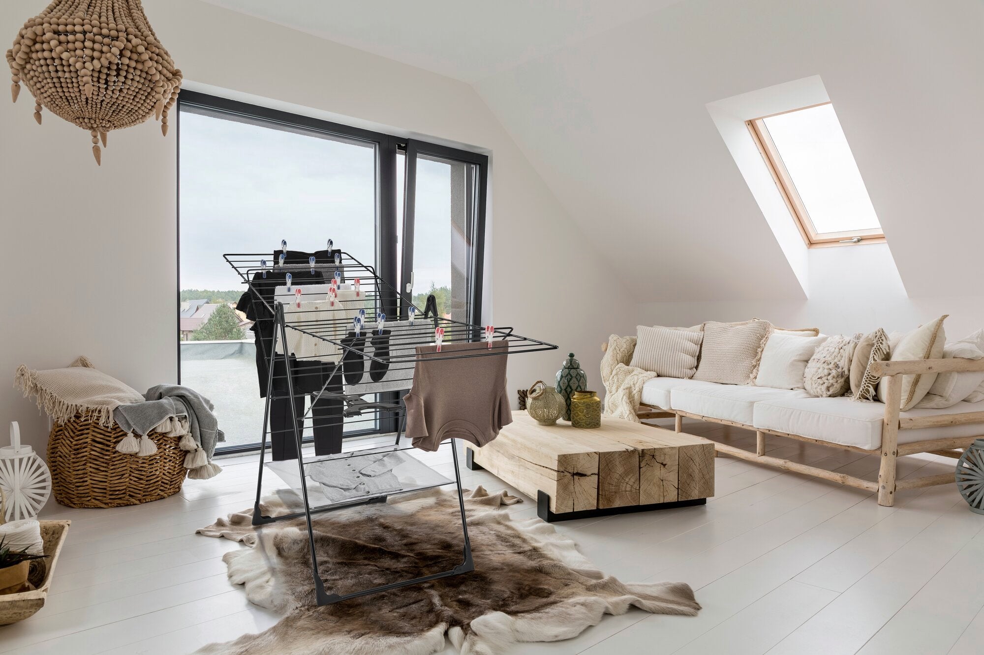 Standtrockner Classic 250 Flex in einem modernen Wohnzimmer mit großen Fenstern. Der Trockner ist mit Kleidung beladen und steht auf einem Teppich, umgeben von stilvollen Möbeln.