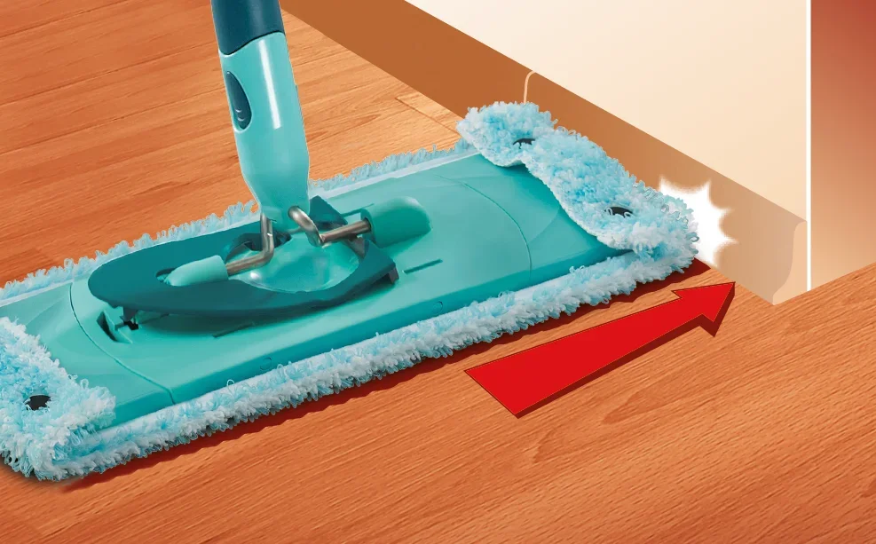 Mop CLEAN TWIST w kolorze turkusowym dokładnie czyści podłogę wzdłuż ściany. Czerwona strzałka wskazuje łatwy dostęp do trudno dostępnych miejsc.