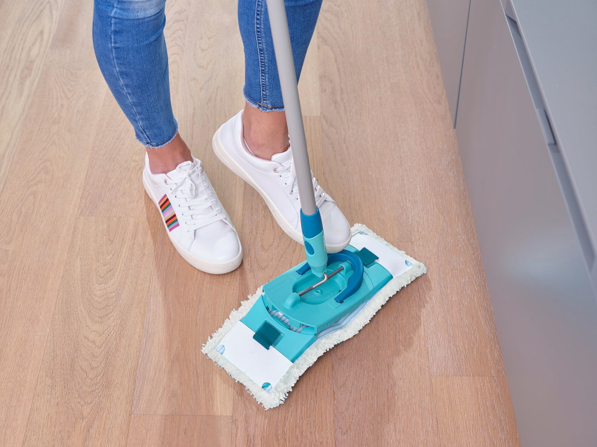 Een persoon maakt een houten vloer schoon met de CLEAN TWIST M Ergo micro duo. De mop heeft een ergonomisch ontwerp en is ideaal voor grondig en eenvoudig schoonmaken.