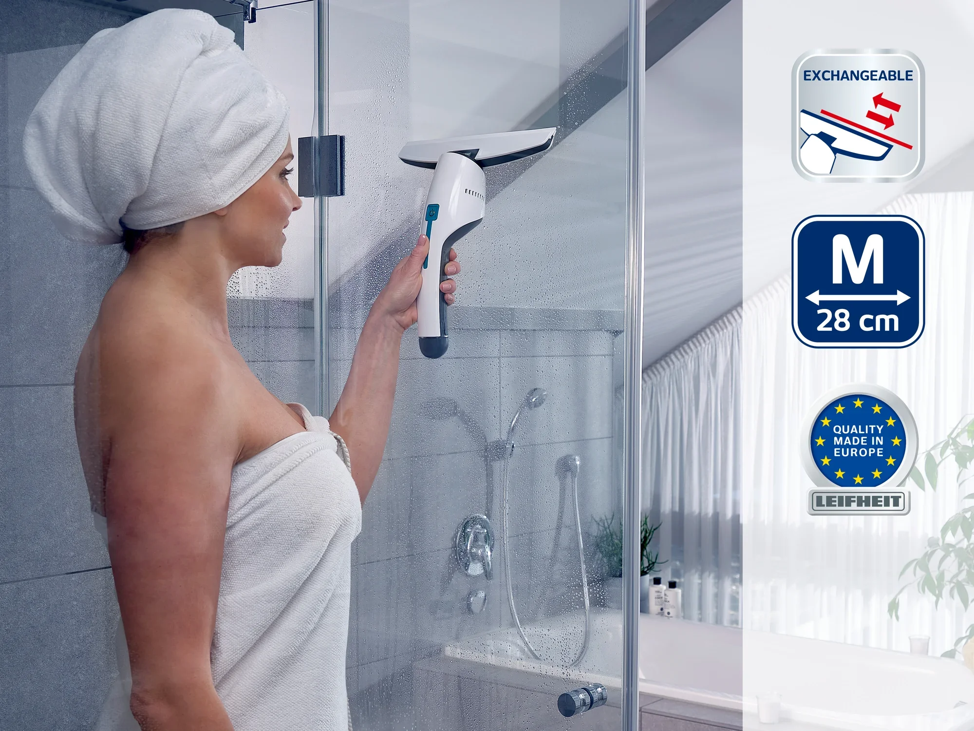 Kobieta w ręczniku używa myjki do okien do czyszczenia ściany prysznica. Urządzenie ma wymienne ostrze i szerokość 28 cm. Jakość Made in Europe.