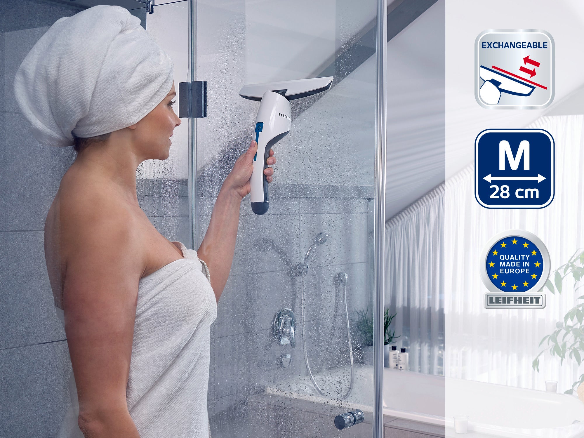 Une femme en serviette utilise le nettoyeur de vitres pour nettoyer une paroi de douche. L'appareil est équipé d'une lame interchangeable et mesure 28 cm de large. Qualité Made in Europe.