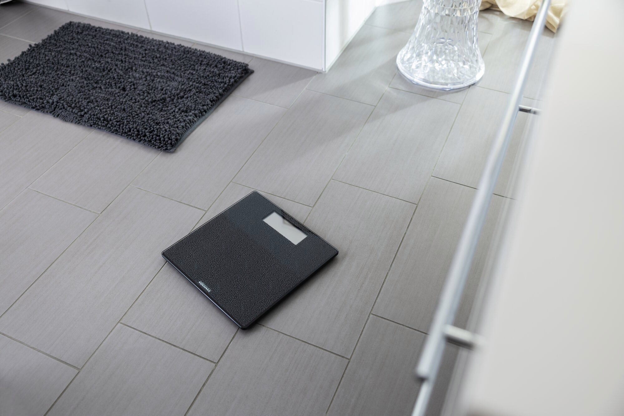 Digitale Personenwaage Style Sense Comfort Coral auf einem Badezimmerboden. Die Waage hat ein modernes Design und eine klare Anzeige, ideal für präzise Gewichtsmessungen.