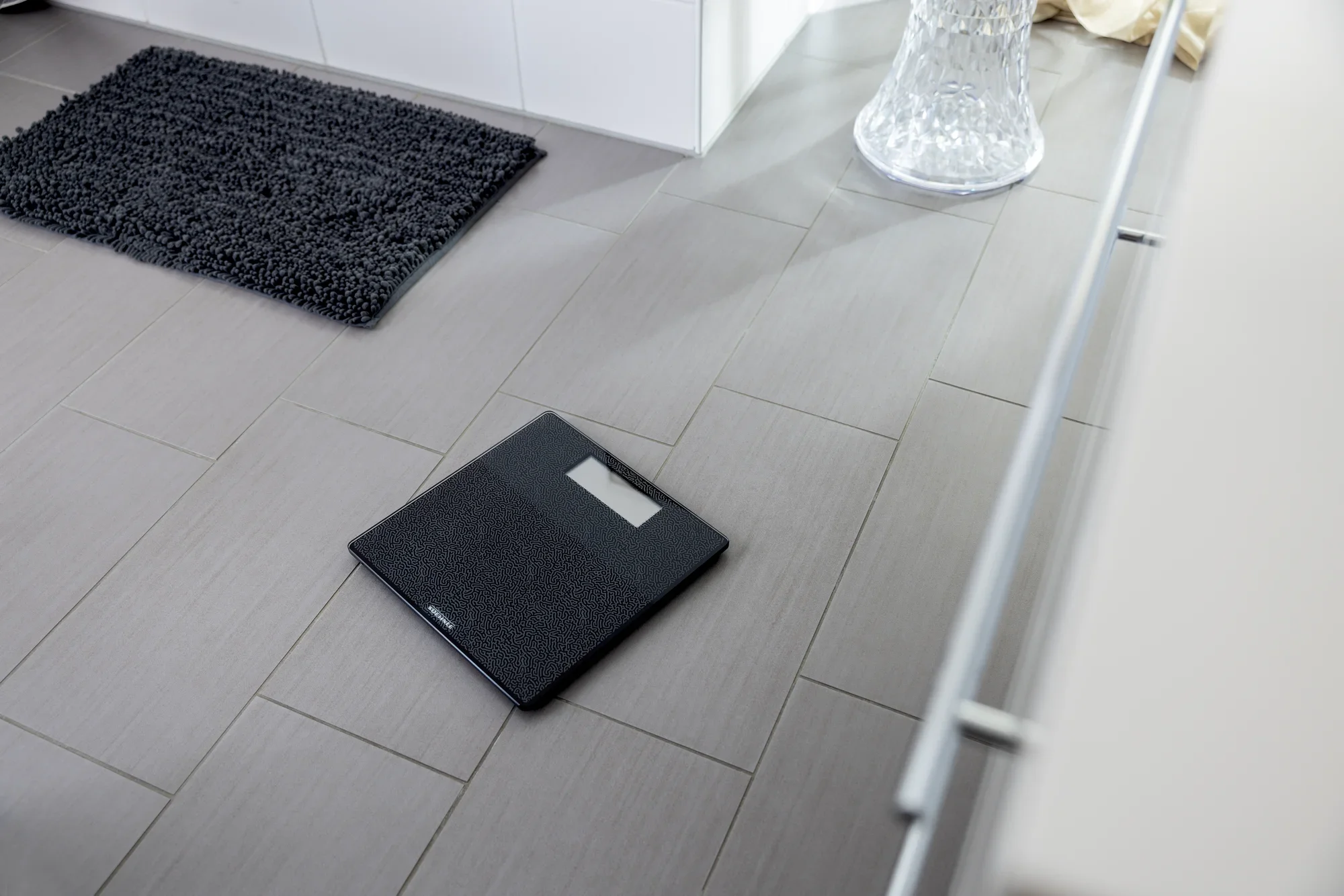 Cyfrowa waga łazienkowa Style Sense Comfort Coral na podłodze w łazience. Waga ma nowoczesny design i przejrzysty wyświetlacz, idealny do precyzyjnych pomiarów masy ciała.