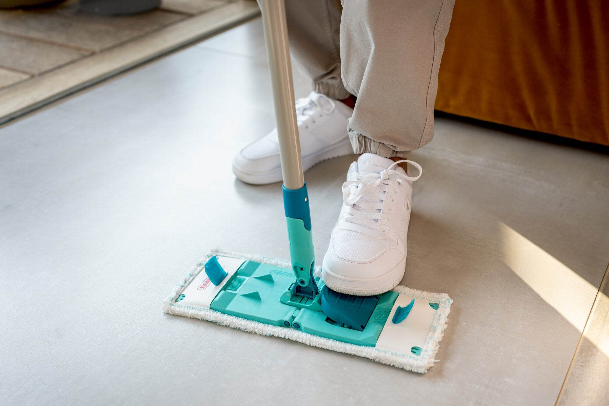 Leifheit POWER CLEAN lavapavimenti con panno in microfibra e snodo flessibile, usato su un pavimento liscio in interni; il piede blocca la base per una pulizia comoda e precisa negli angoli.