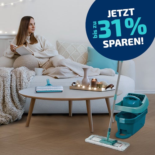 Eine Frau sitzt auf der Couch. Neben ihr stehen zwei Wischsysteme und ein Dampfreiniger