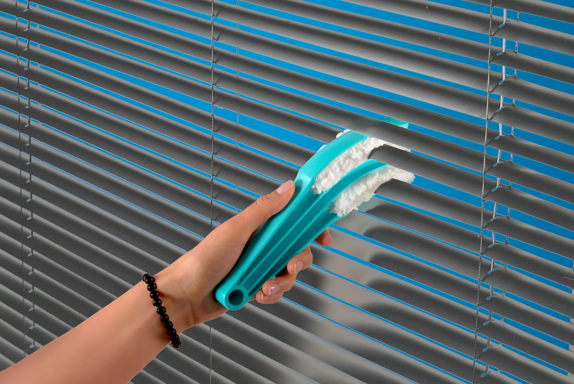 Eine Hand hält den Leifheit Jalousienreiniger Jalousetta, der speziell für die Reinigung von Jalousien entwickelt wurde. Der Reiniger hat drei Bürsten, die gleichzeitig mehrere Lamellen säubern können. Ideal für eine effiziente und gründliche Reinigung.