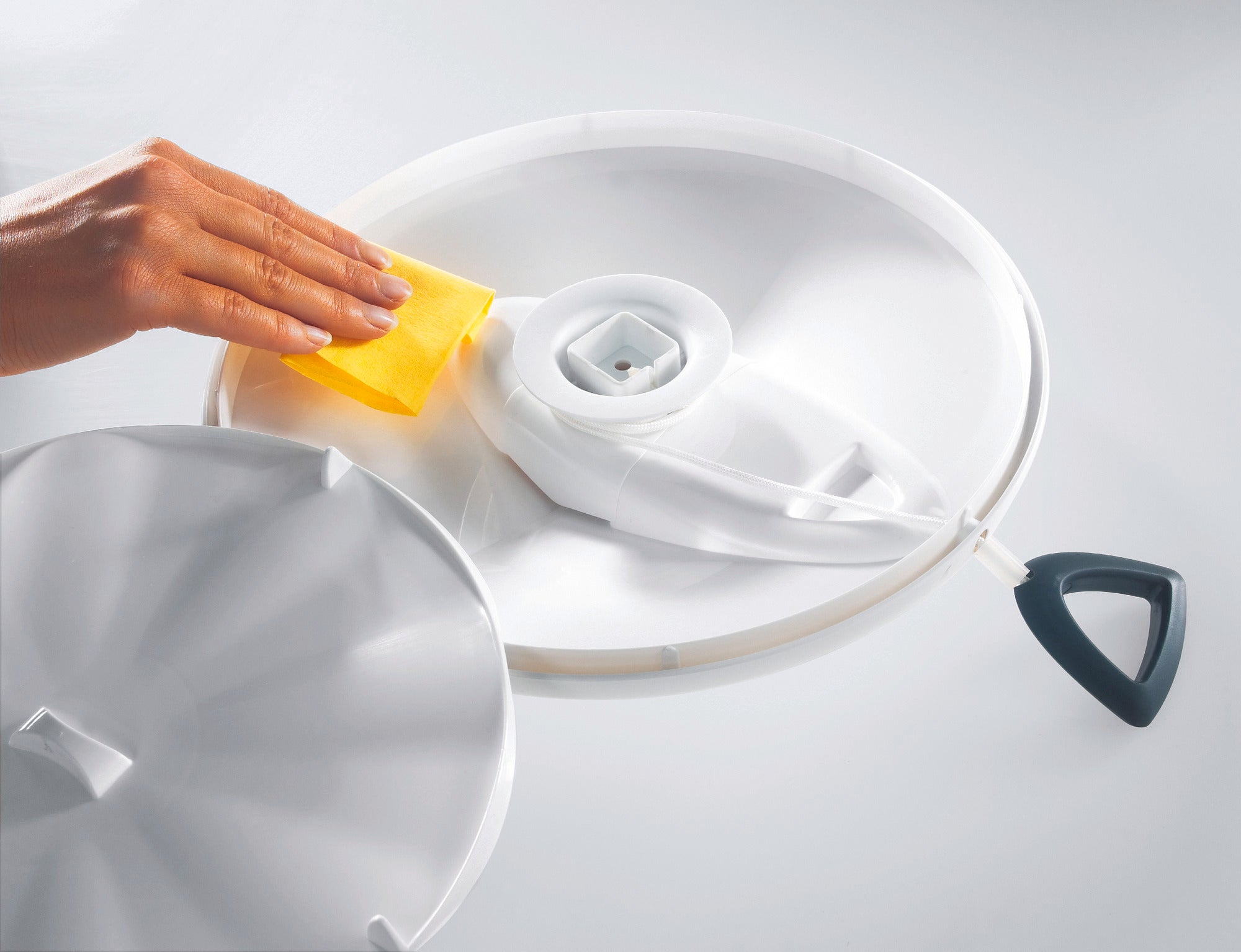 Escurridor de ensaladas de 5,5 l: una mano limpia el escurridor de ensaladas blanco con una esponja amarilla. La tapa se puede quitar para facilitar la limpieza. Ideal para ensaladas frescas.