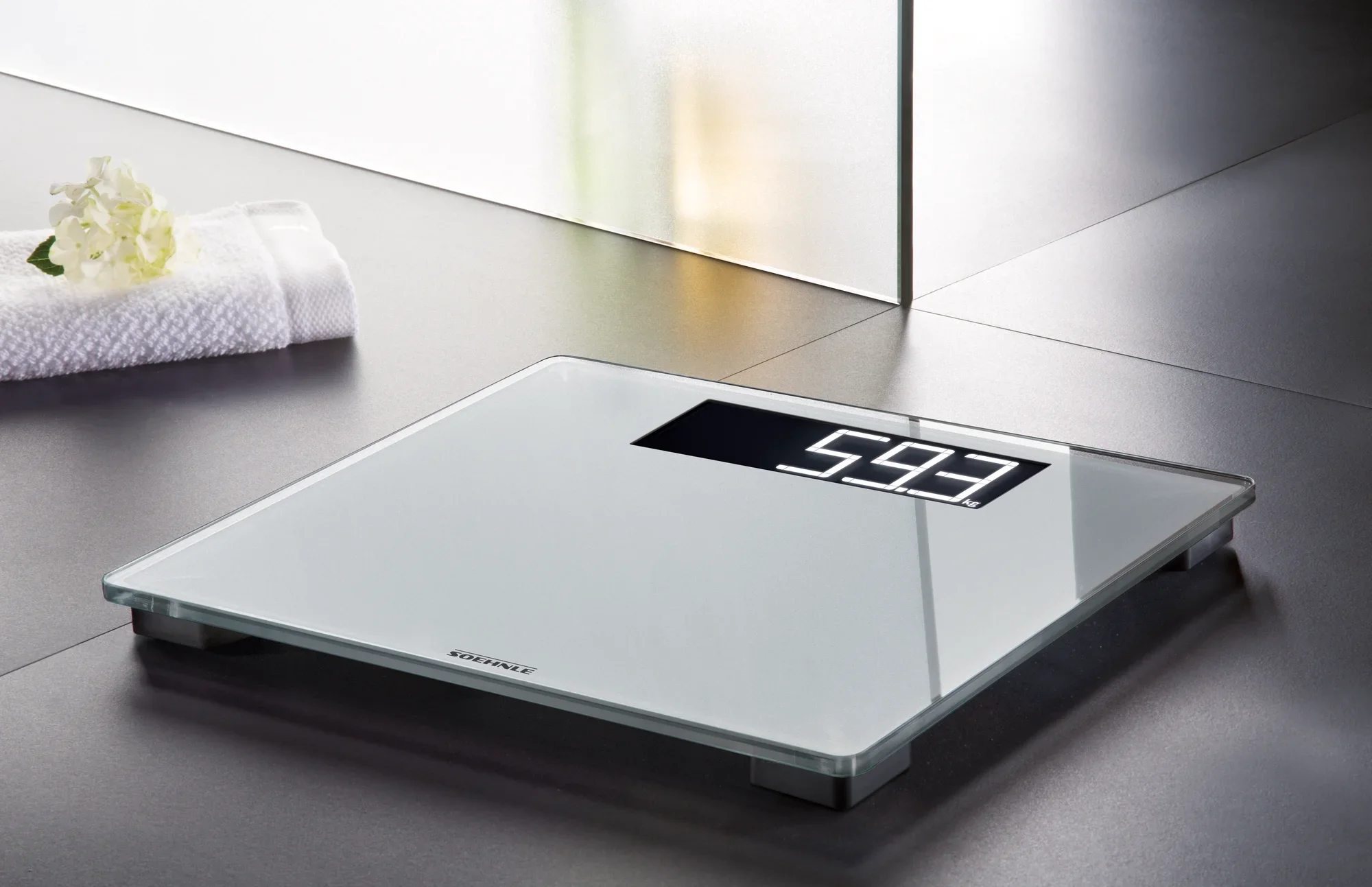 Cyfrowa waga łazienkowa Style Sense Comfort 600 na podłodze w nowoczesnej łazience. Waga wskazuje 59,3 kg i ma elegancki, minimalistyczny wygląd.