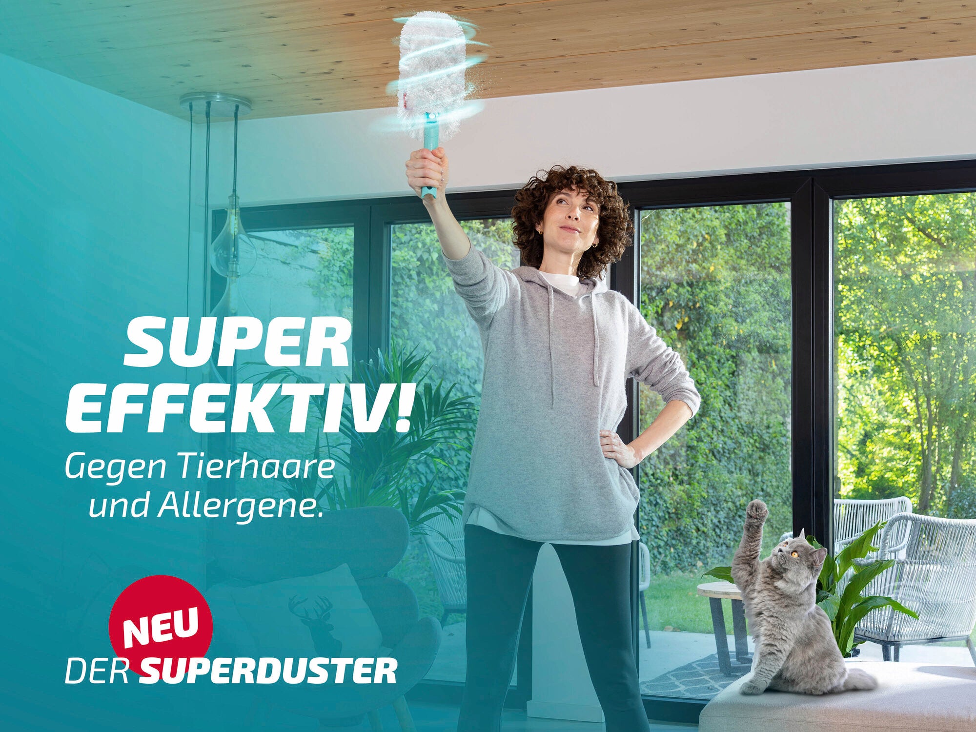 Eine Frau benutzt den Leifheit Superduster, um Staub von der Decke zu entfernen. Der Text auf dem Bild hebt die Effektivität gegen Tierhaare und Allergene hervor. Ein neugieriger grauer Kater sitzt auf einem Sofa im Hintergrund.