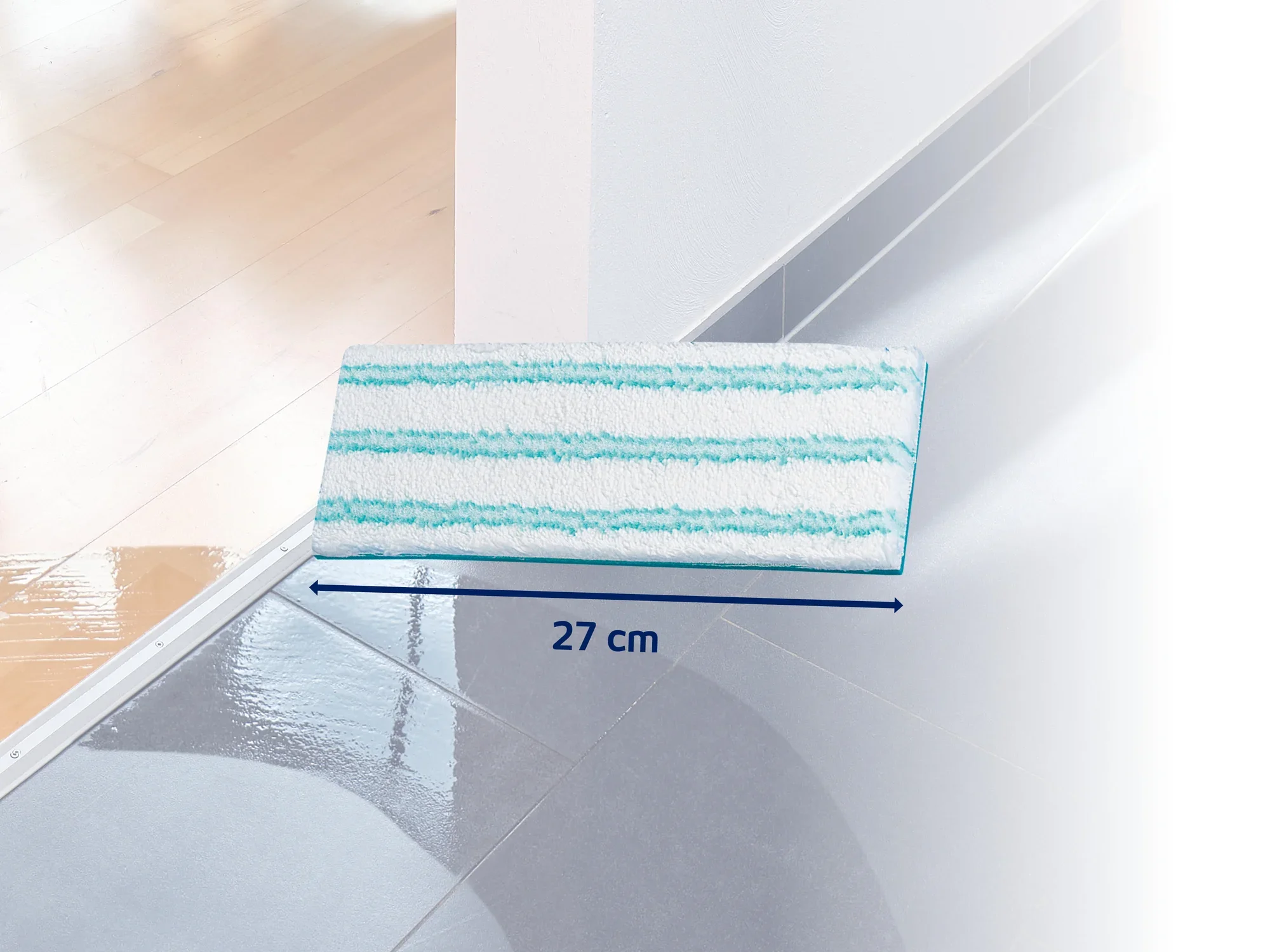 Ein rechteckiger Wischmopp-Aufsatz mit blauen Streifen liegt auf einem glänzenden, sauberen Boden. Der Aufsatz ist 27 cm breit und eignet sich ideal für die gründliche Reinigung von Hartböden.