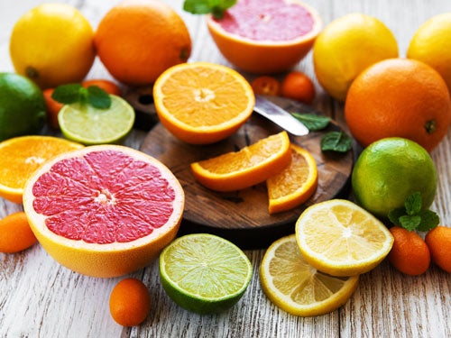 Verschiedene frische, aufgeschnittene Zitrusfruechte wie Grapefruit, Orange, Limette, und Zitrone auf einem rustikalen Holztisch.