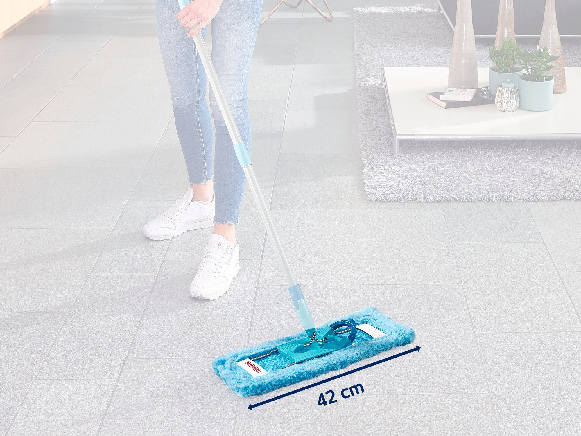Eine Person reinigt einen grauen Fliesenboden mit einem blauen Leifheit 55118 Bodenwischer. Der Wischmopp hat eine Breite von 42 cm und ist ideal für große Flächen geeignet.