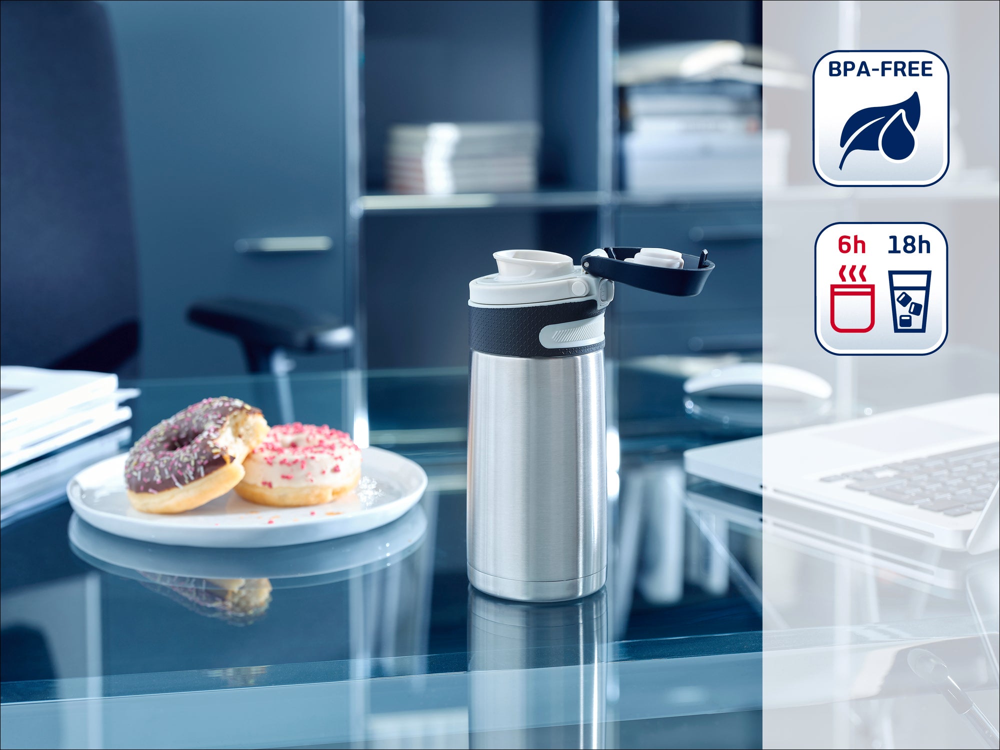 Une bouteille thermos en acier inoxydable est posée sur un bureau moderne à côté d'une assiette avec des beignets. La bouteille est sans BPA et garde les boissons chaudes pendant 6 heures et froides pendant 18 heures.