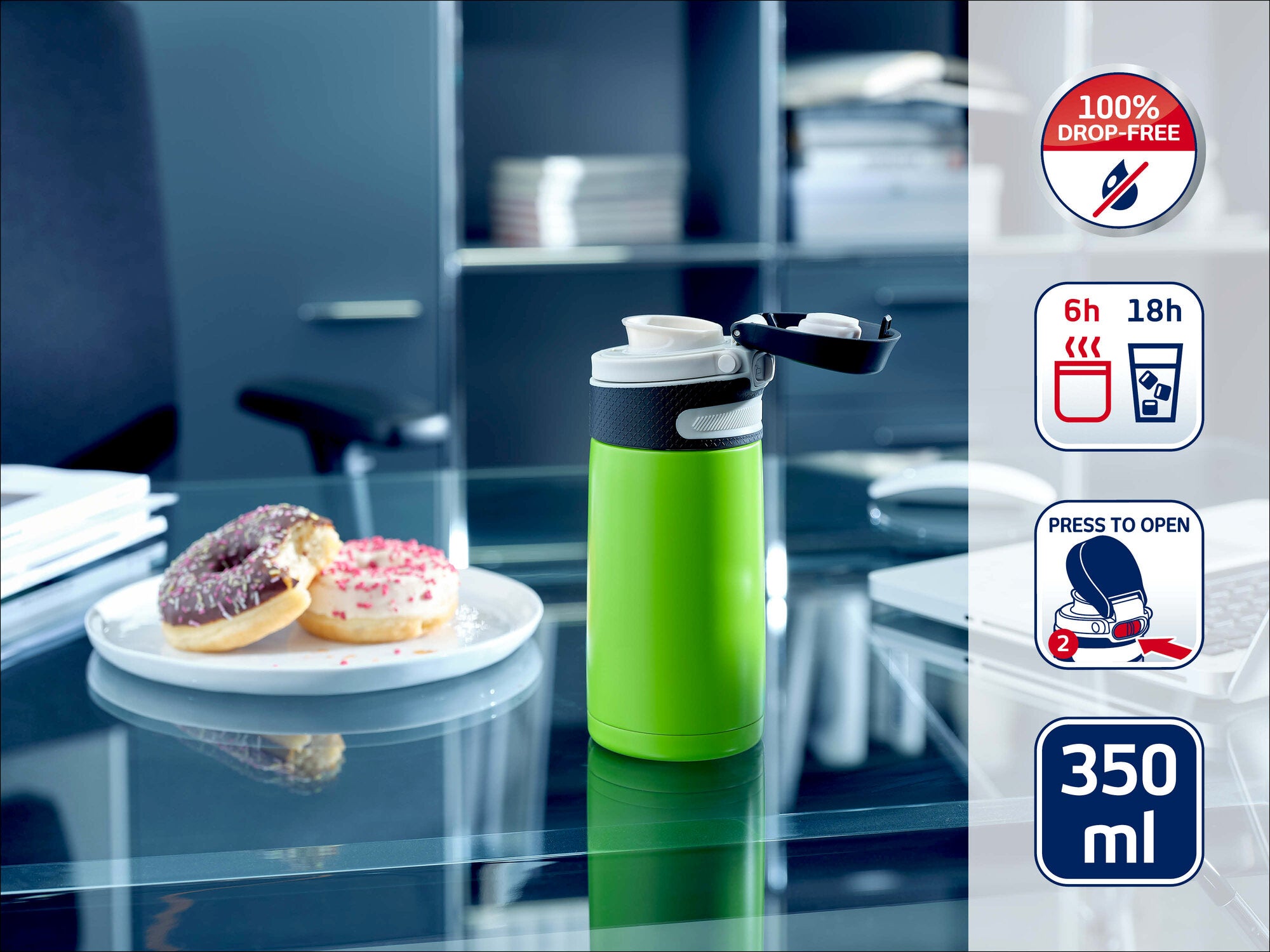Leifheit Isolierbecher to go 350 ml in Grün auf einem Glastisch im Büro, mit geöffnetem Trinkverschluss neben einem Teller mit zwei Donuts; seitlich Icons zu auslaufsicher, 6 h warm, 18 h kalt und Press-to-open.
