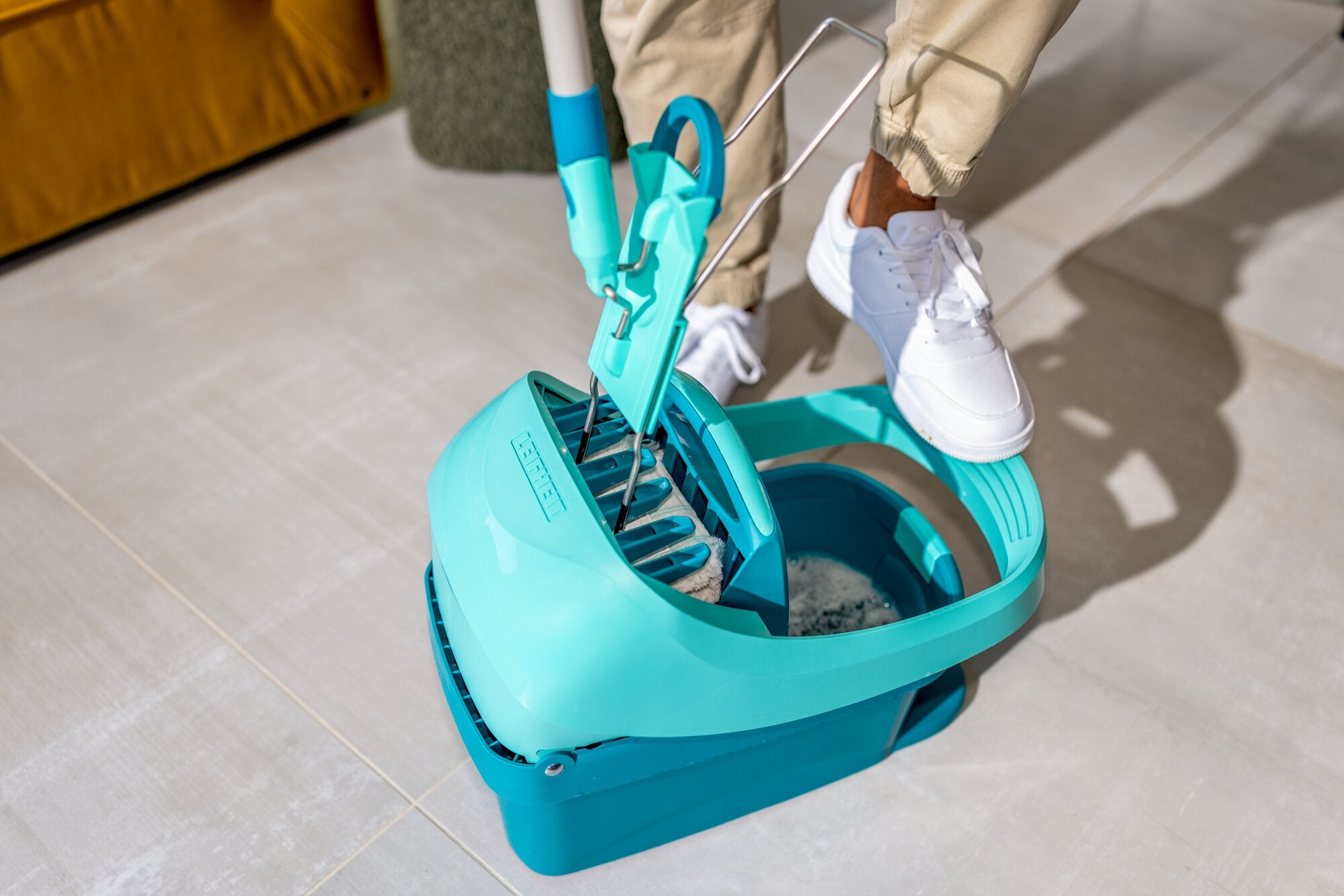 Presse à serpillière Leifheit Profi XL en turquoise pour essorer le balai de sol : le support rabattable est introduit dans la presse au pied, pour un nettoyage hygiénique sans se pencher ni se mouiller les mains.