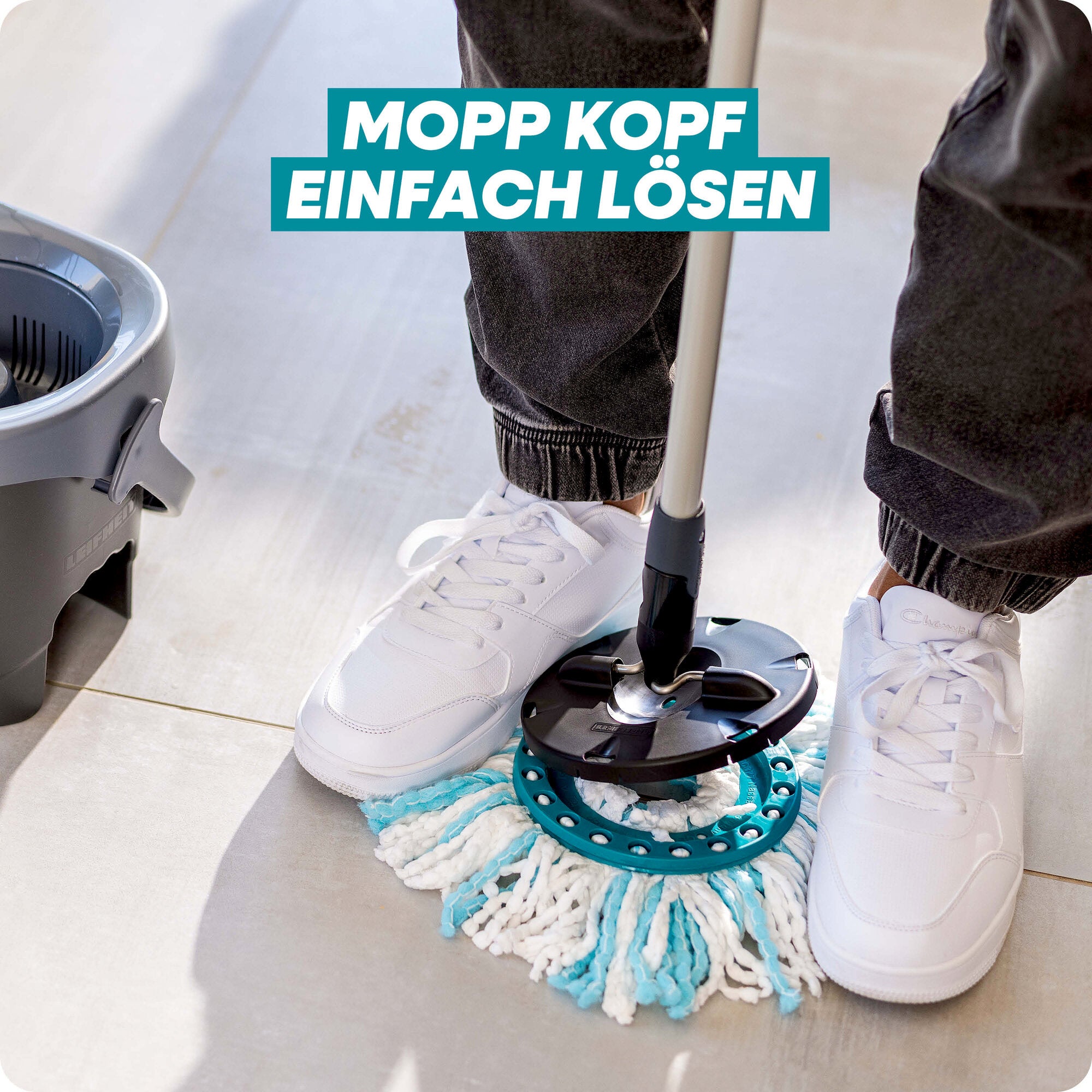 Leifheit Set CLEAN TWIST Disc Mop Black: Eine Person löst den Moppkopf des lavapavimenti-Systems per Fußdruck am Stiel, neben dem Eimer auf hellem Boden; Hinweis im Bild: „Mopp Kopf einfach lösen“.