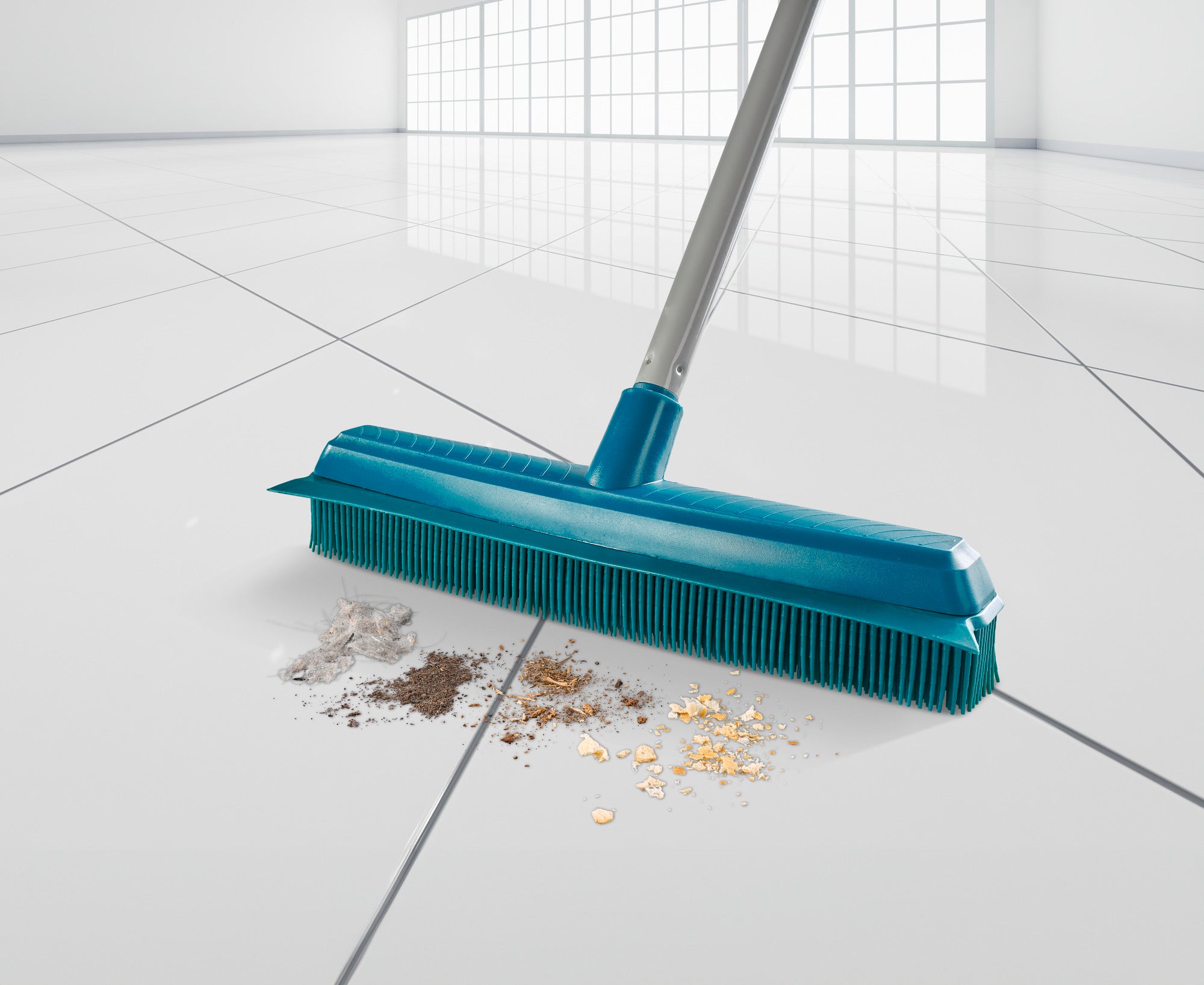 Een turquoise gekleurde superbezem maakt effectief een glanzend witte tegelvloer schoon. De bezem verwijdert vuil, stof en kleine deeltjes voor een vlekkeloze schoonmaak.