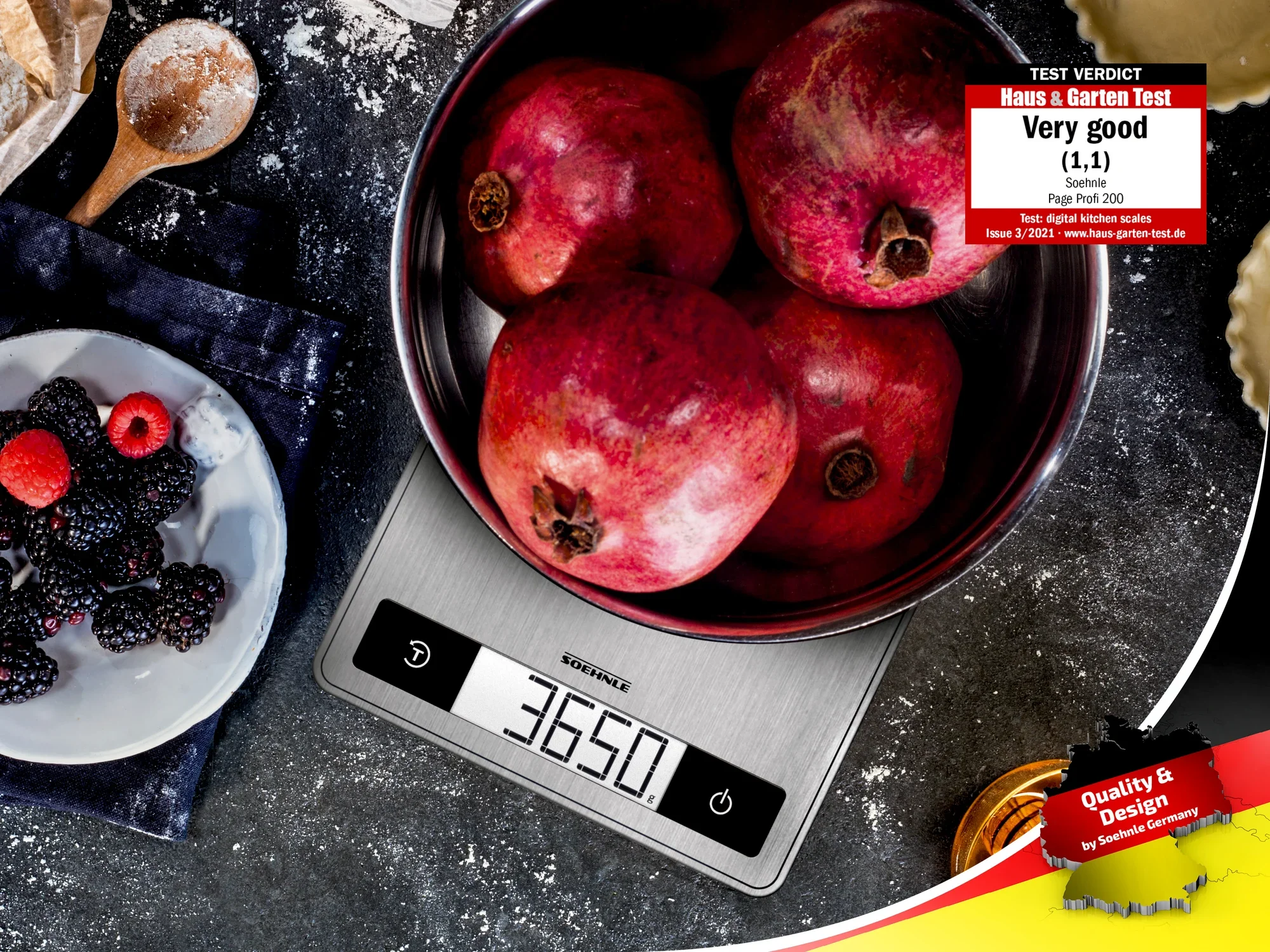 Eine digitale Küchenwaage von Soehnle zeigt das Gewicht von vier Granatäpfeln in einer Schüssel an. Daneben liegen Beeren und Brot. Die Waage erhielt eine Bewertung von "Sehr gut" im Test.
