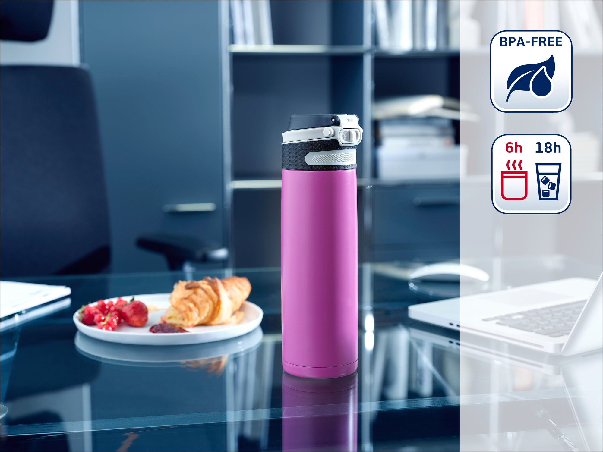 A purple thermos flask stands on a modern office desk next to a plate of pastries. The flask is BPA-free and keeps drinks hot for 6 hours and cold for 18 hours.
