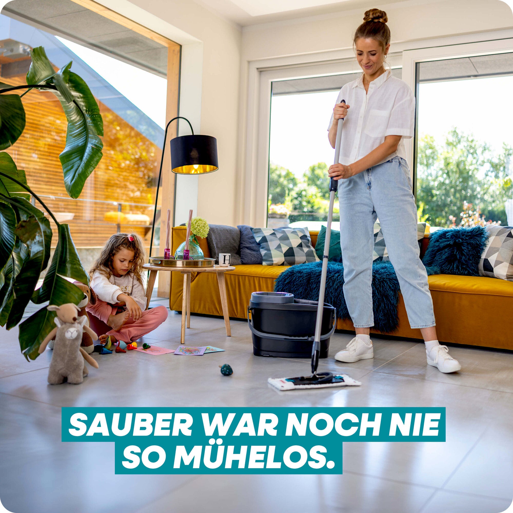 Leifheit Set CLEAN TWIST M Black: Eine Frau wischt mühelos den hellen Boden im Wohnzimmer, während ein Kind spielt; moderner Flachwischer und schwarzes Eimersystem im stilvollen Wohnambiente.