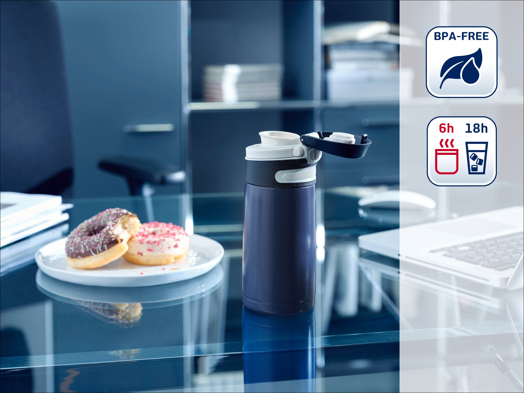 Eine Thermoskanne steht auf einem Schreibtisch neben einem Teller mit Donuts. Die Kanne ist BPA-frei und hält Getränke 6 Stunden heiß und 18 Stunden kalt. Ideal für das Büro.
