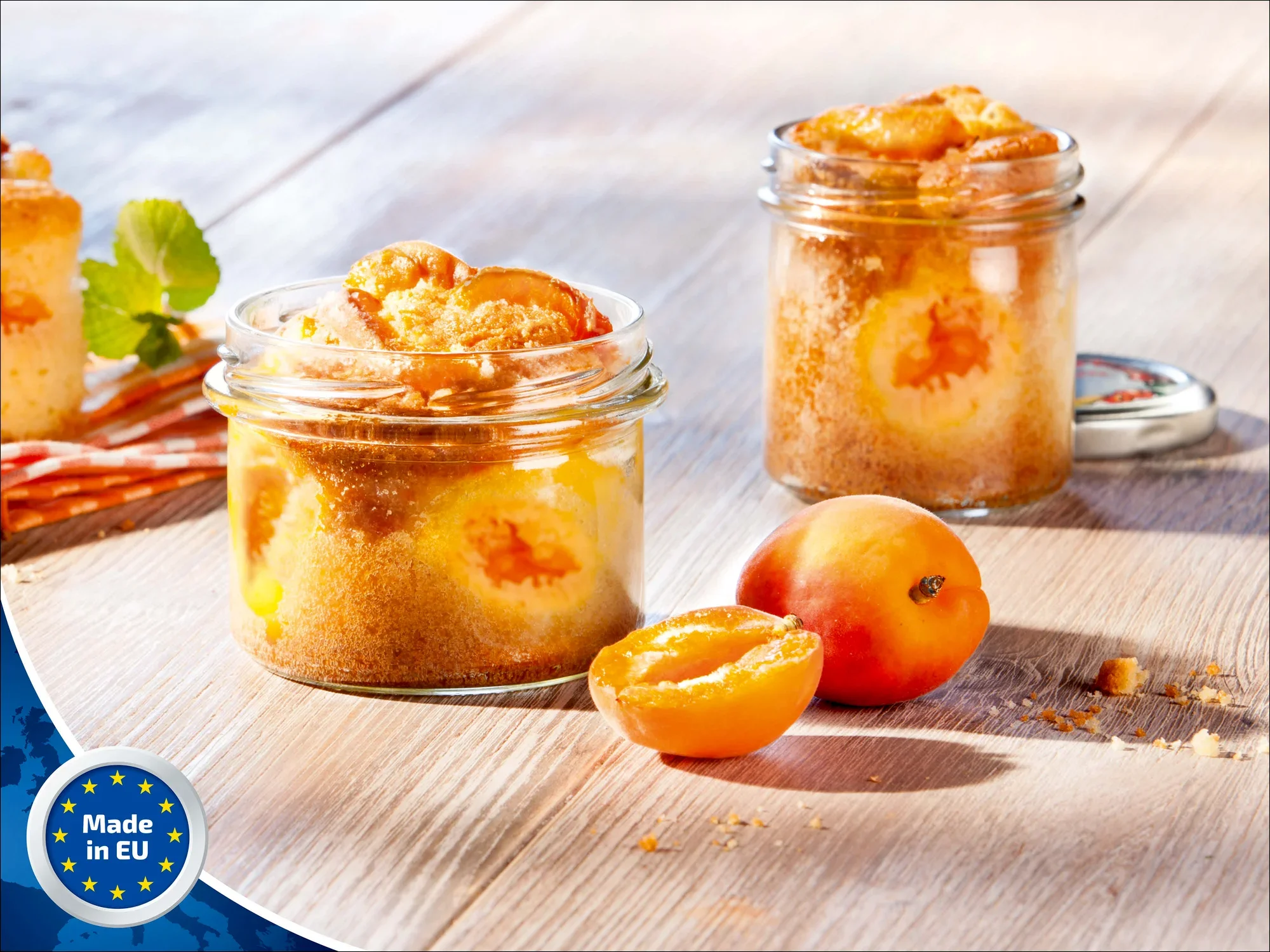 Ein Leifheit Sturzglas mit 235 ml Fassungsvermögen, gefüllt mit einem Aprikosenkuchen. Das Glas steht auf einem Holztisch, daneben frische Aprikosen. Im Hintergrund ein weiteres Glas.