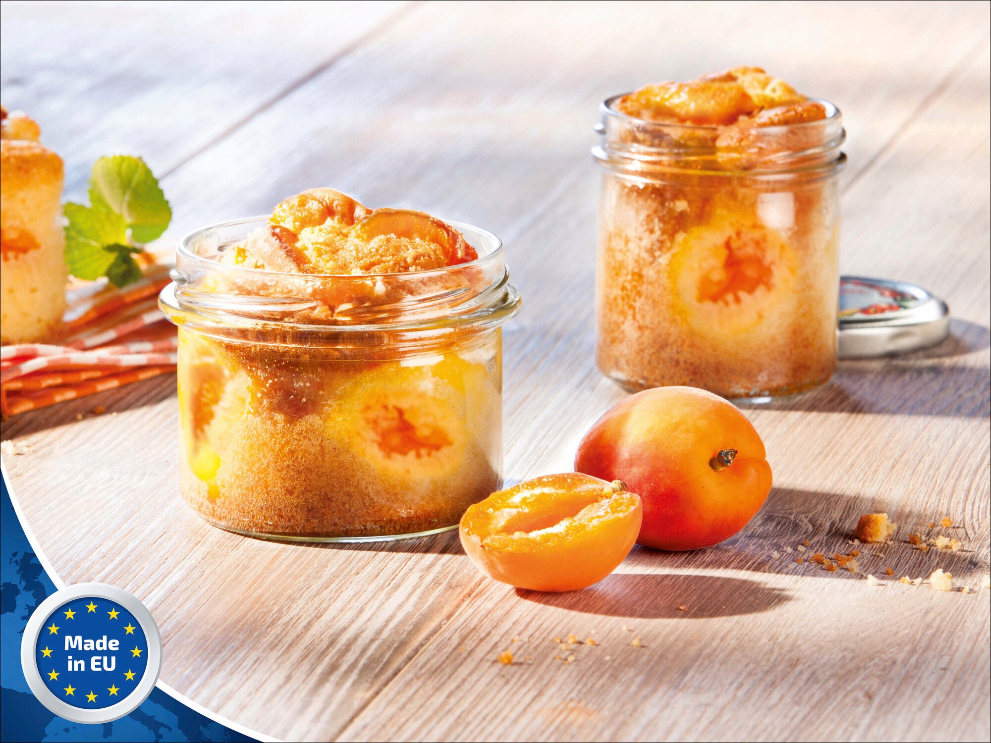 Ein Leifheit Sturzglas mit 235 ml Fassungsvermögen, gefüllt mit einem Aprikosenkuchen. Das Glas steht auf einem Holztisch, daneben frische Aprikosen. Im Hintergrund ein weiteres Glas.