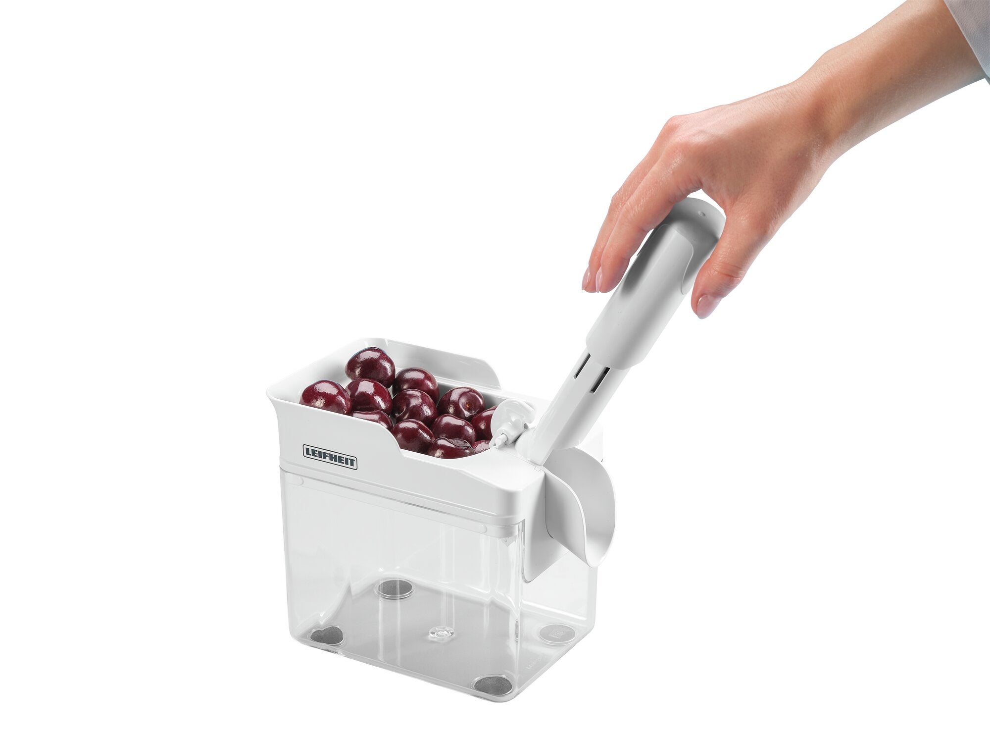 Kirschentkerner Cherrymat in Aktion: Eine Hand bedient den weißen Kirschentkerner, der Kirschen in einem transparenten Behälter entkernt. Ideal für schnelles und einfaches Entkernen.
