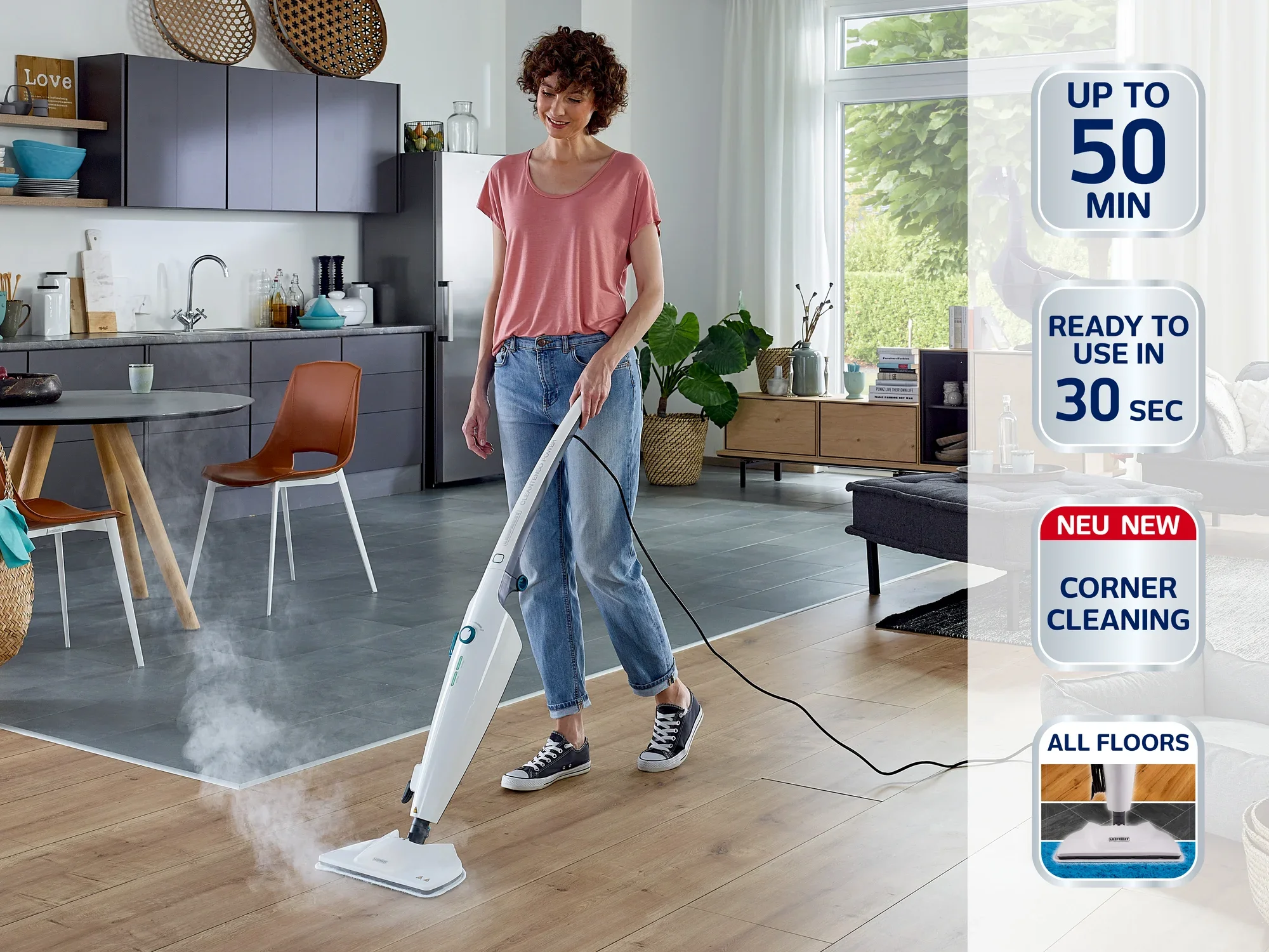 Une femme nettoie le sol en bois d'une cuisine moderne à l'aide d'un nettoyeur vapeur. Le nettoyeur offre jusqu'à 50 minutes d'autonomie, est prêt à l'emploi en 30 secondes et convient à tous les types de sols.