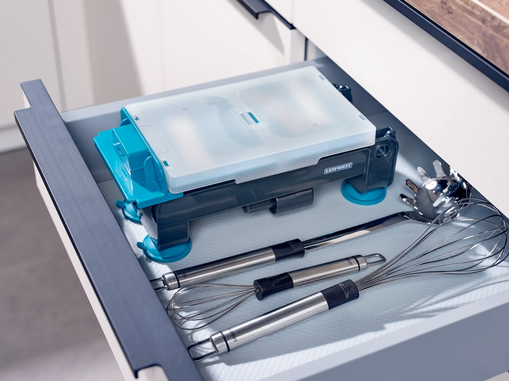 In einer Küchenschublade liegt ein Tisch-Spiralschneider, ordentlich verstaut neben Schneebesen und Küchenutensilien. Der Spiralschneider ist kompakt und platzsparend.