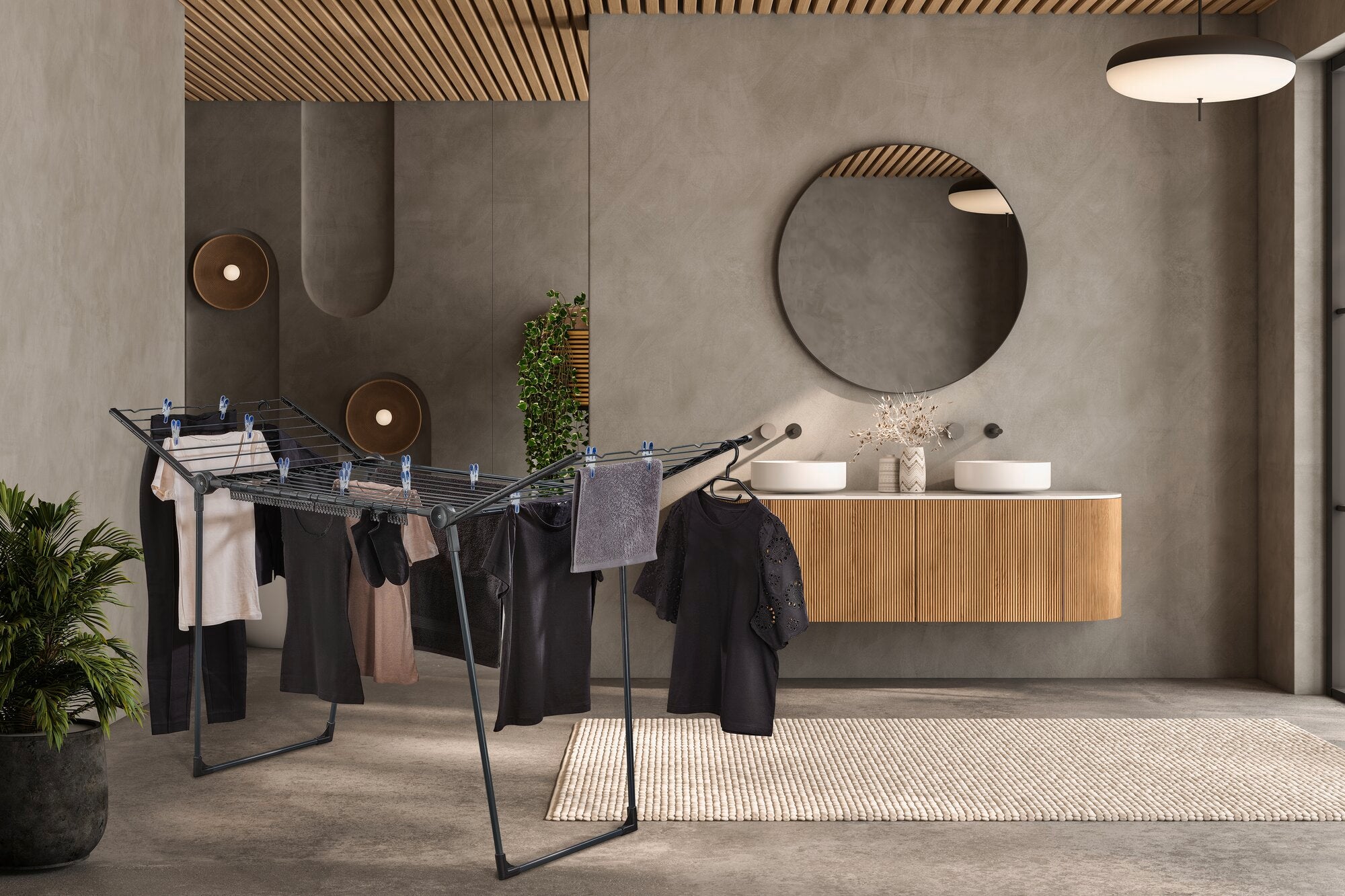 Modernes Badezimmer mit Holzdecke. In der Mitte steht ein schwarzer Wäscheständer mit hängender Kleidung.