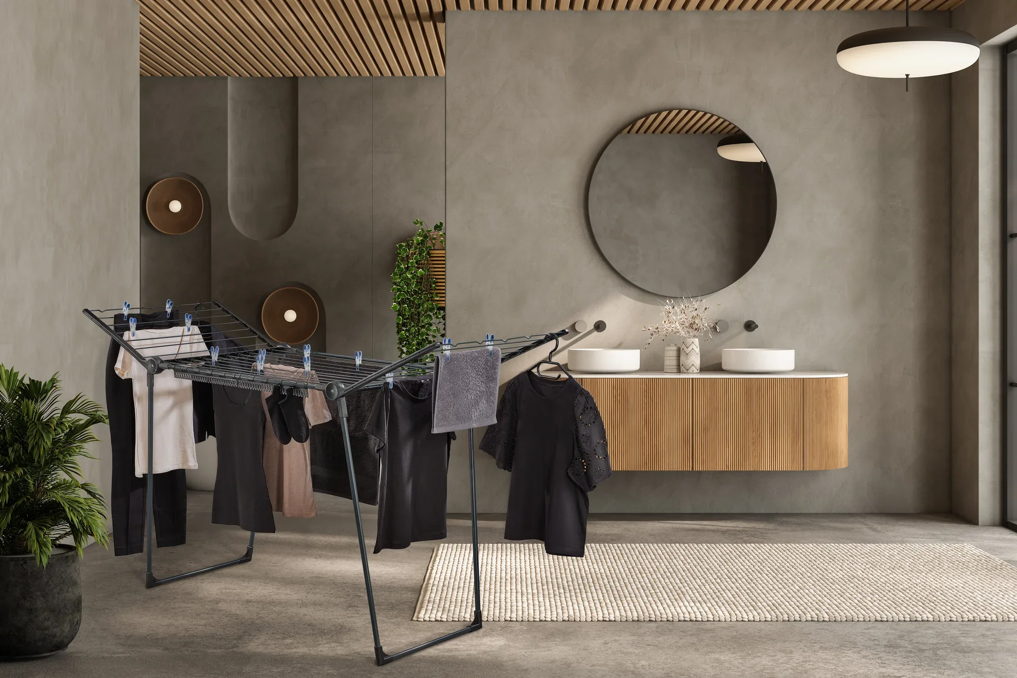 Modernes Badezimmer mit Holzdecke. In der Mitte steht ein schwarzer Wäscheständer mit hängender Kleidung.