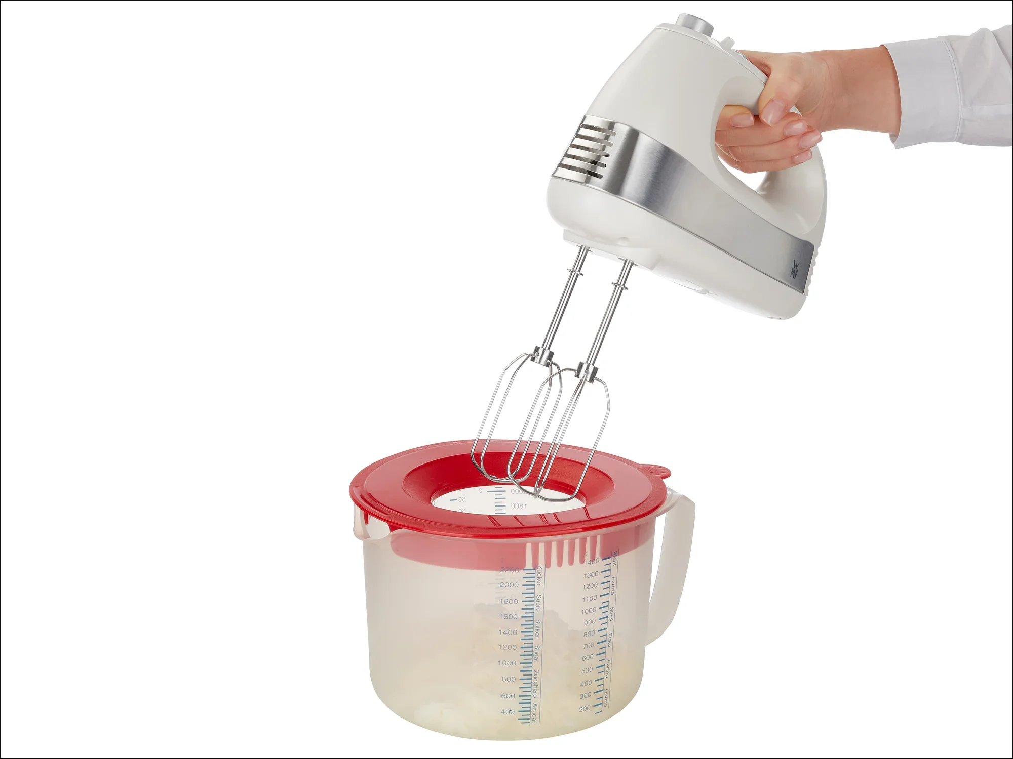 Mikser ręczny trzymany nad przezroczystą miską z czerwoną pokrywką. Mikser ma dwa mieszadła i jest obsługiwany jedną ręką. Idealny do mieszania składników.