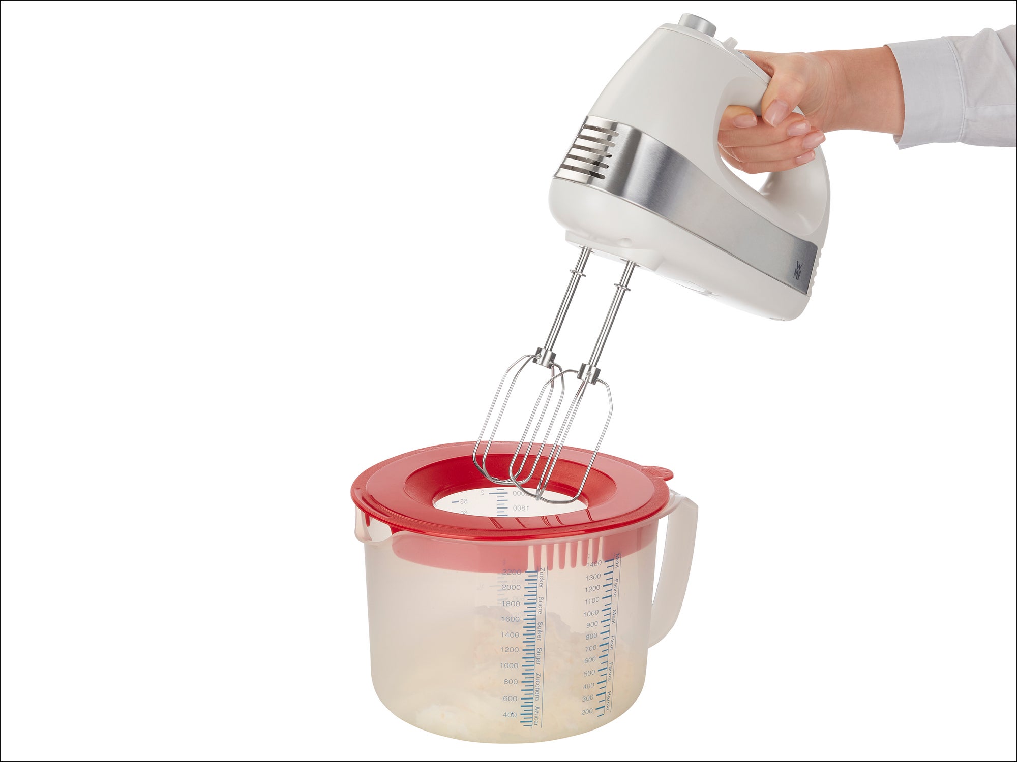 Ein Handmixer wird über einer transparenten Rührschüssel mit rotem Deckel gehalten. Der Mixer hat zwei Rührbesen und wird von einer Hand bedient. Ideal zum Mischen von Zutaten.